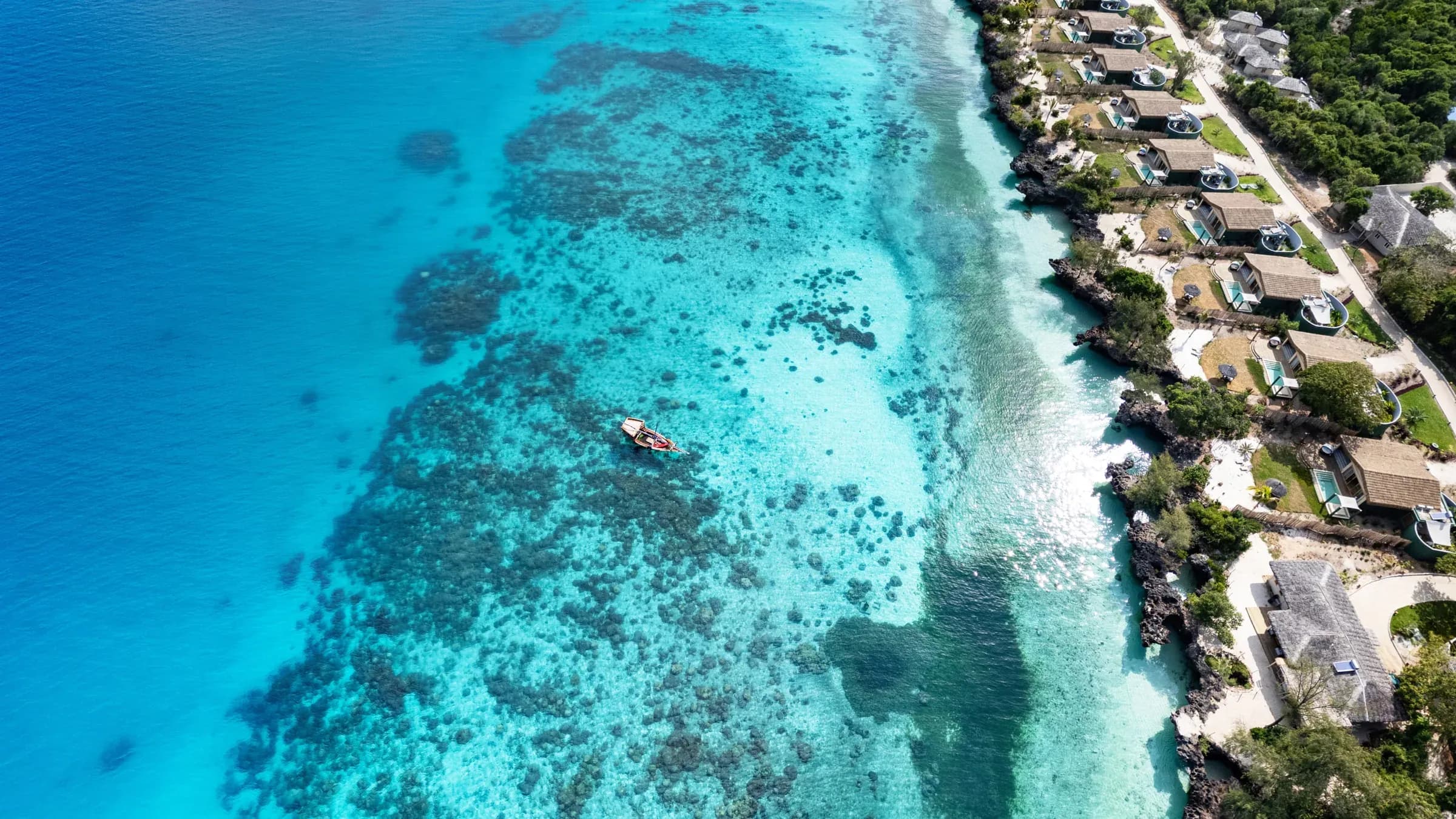 Aerial view of overwater villas along Bawe Island's reef edge