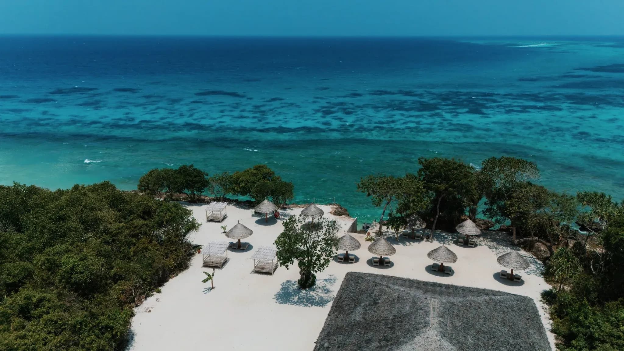 Aerial view of Bawe Island's beach club with thatched umbrellas and turquoise lagoon, Zanzibar