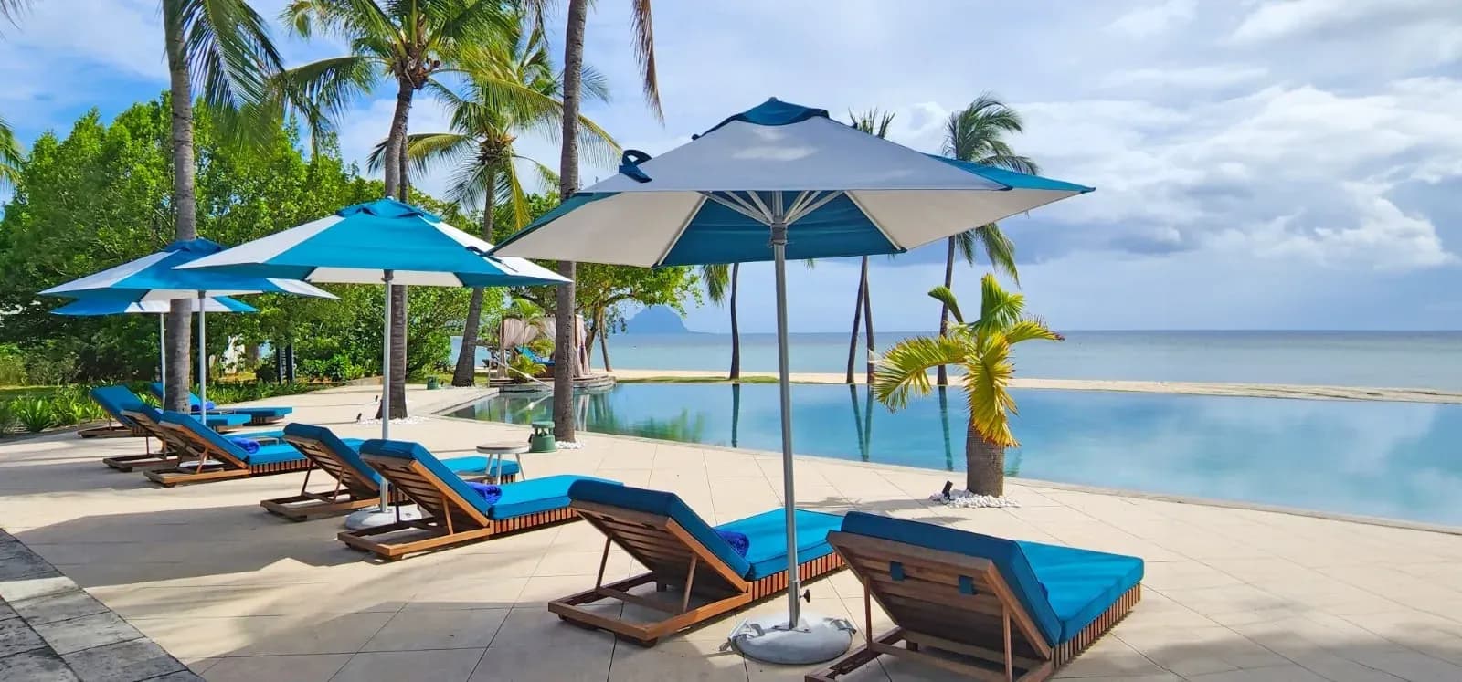 Infinity pool with sun loungers and palm trees facing the lagoon at Maradiva Villas Resort & Spa, Wolmar, Mauritius