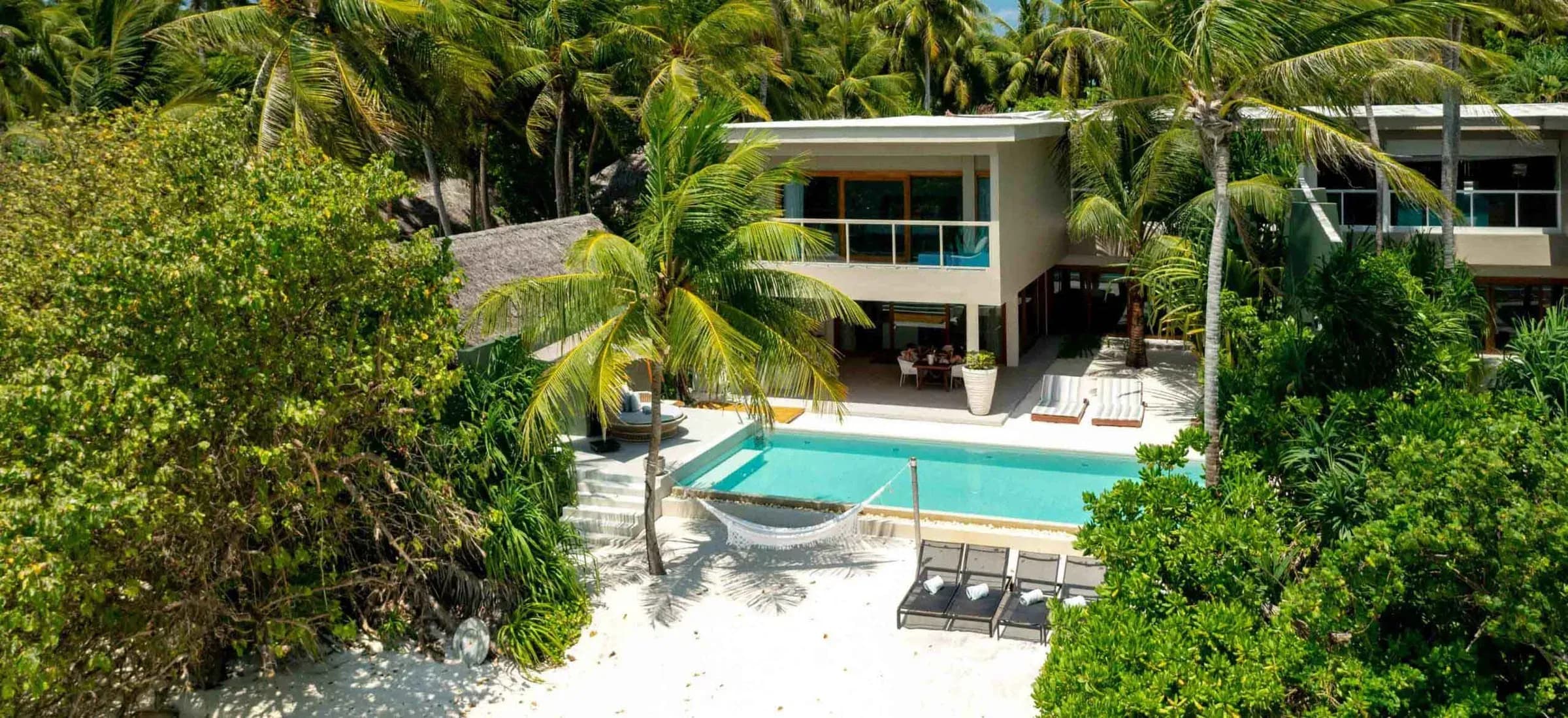 Aerial view of a Four-Bedroom Beach Residence among palms at Amilla Maldives