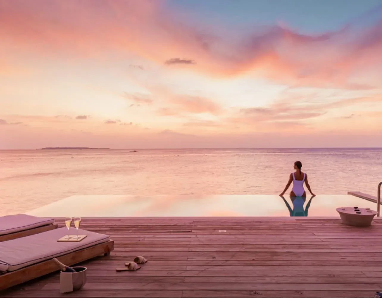 Sunset over the deck and infinity pool of a Water Pool Villa at Amilla Maldives