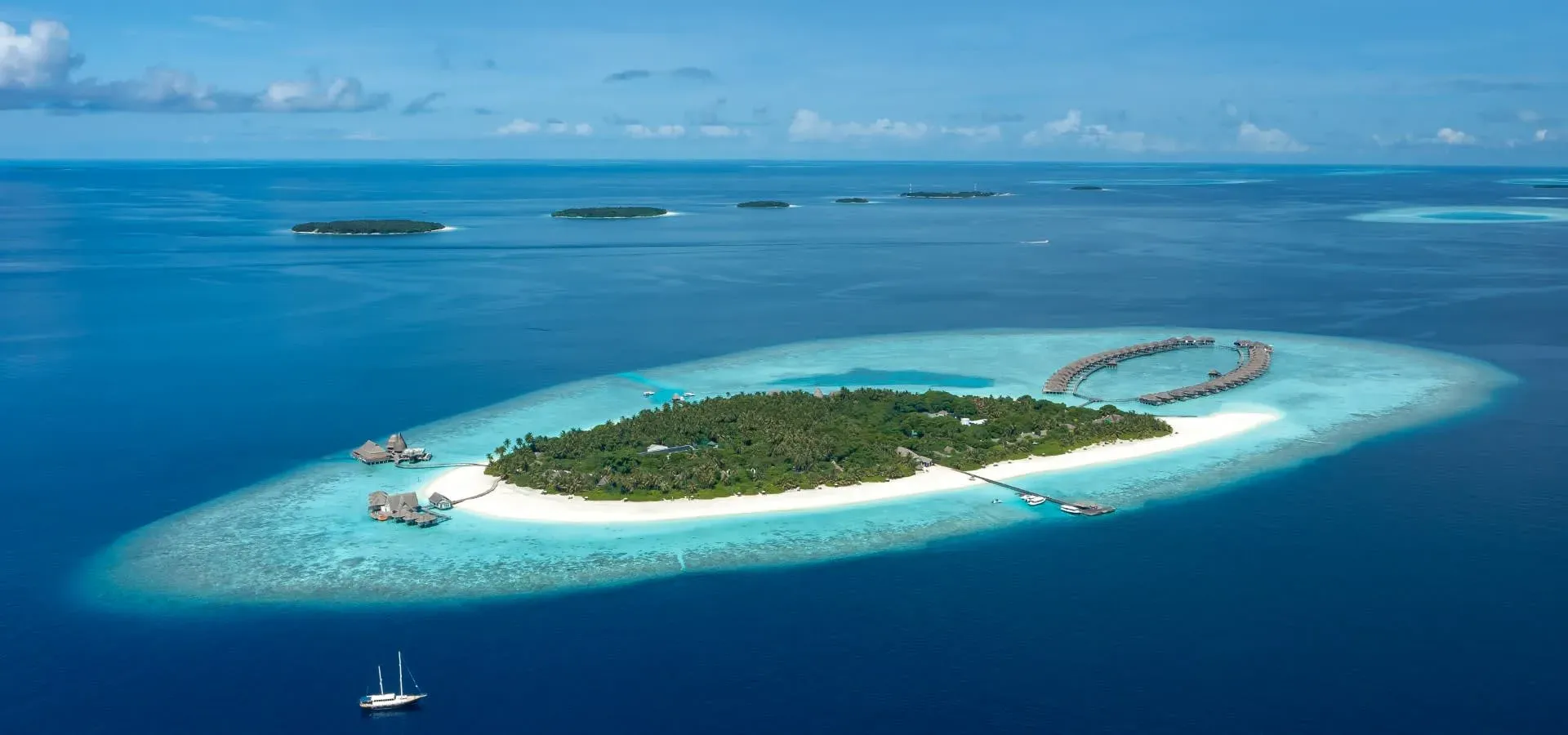 Aerial view of Anantara Kihavah Maldives Villas' overwater and beach villas fringing the Baa Atoll lagoon