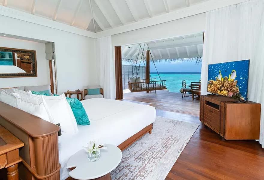 Sunset Over Water Pool Villa bedroom opening to the lagoon at Anantara Kihavah Maldives Villas