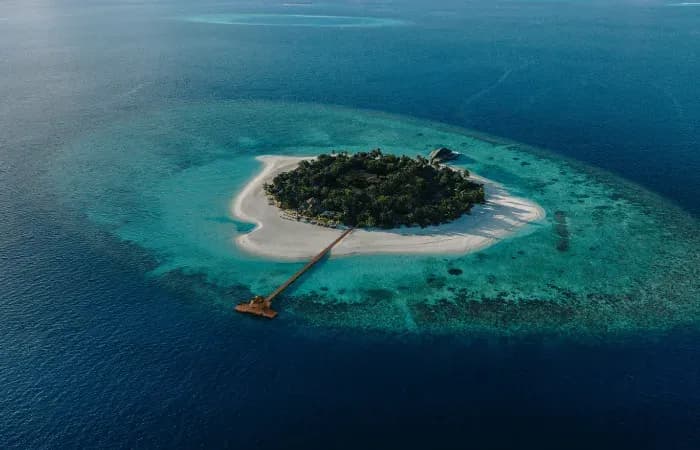Aerial view of Banyan Tree Vabbinfaru's pool villas and turquoise house reef, North Malé Atoll