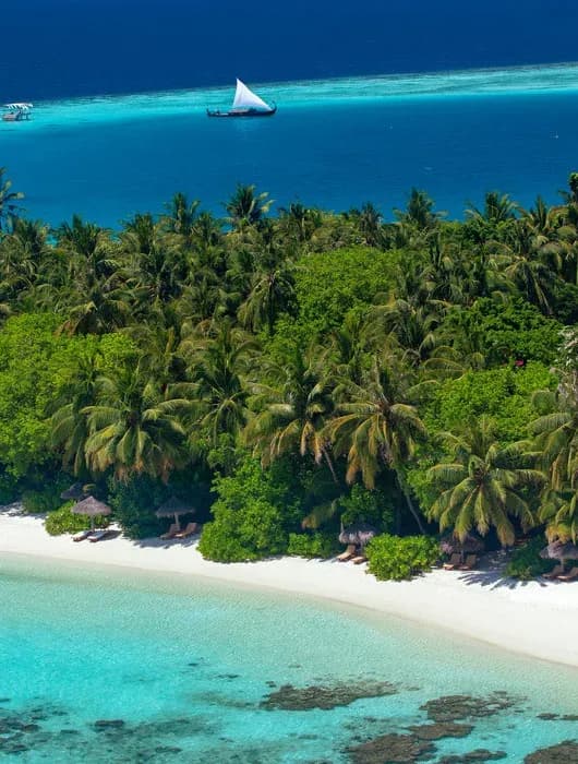 Aerial view of Baros Maldives island fringed by white sand and reef