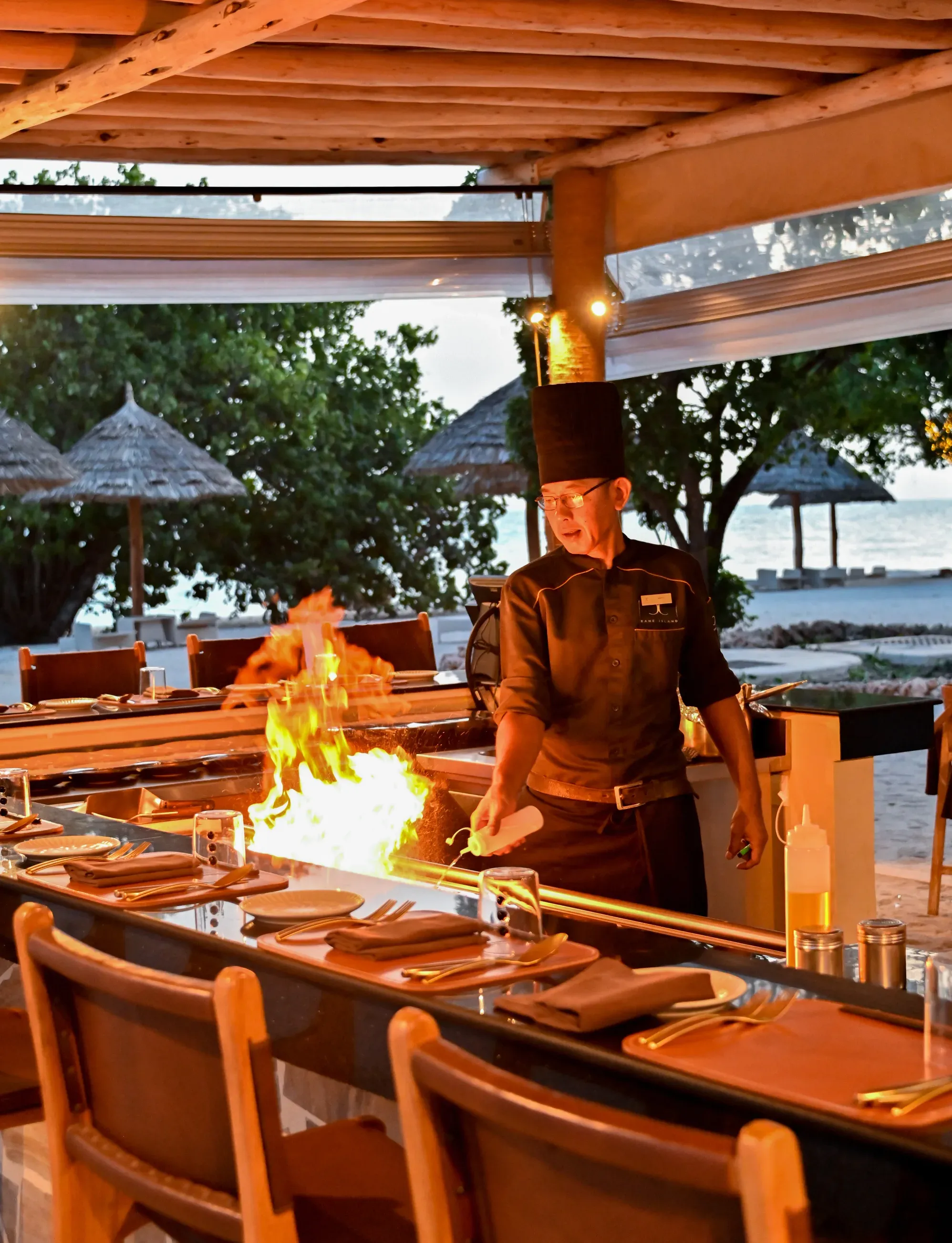 Chef preparing a flaming teppanyaki dish at Rising Sun restaurant, Bawe Island