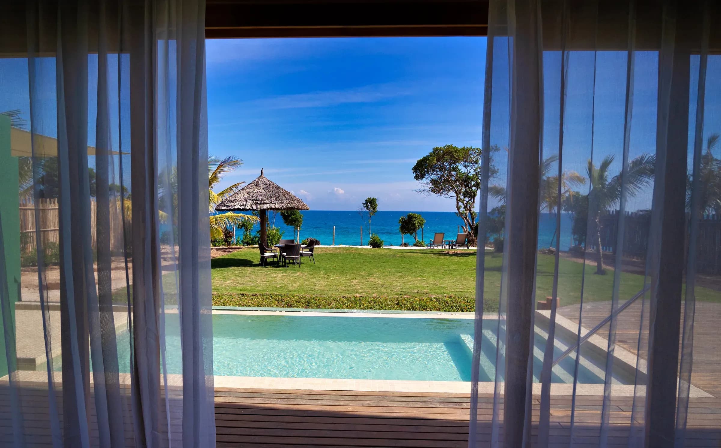 Sea view through the curtains of a Sunrise Villa terrace and plunge pool at Bawe Island