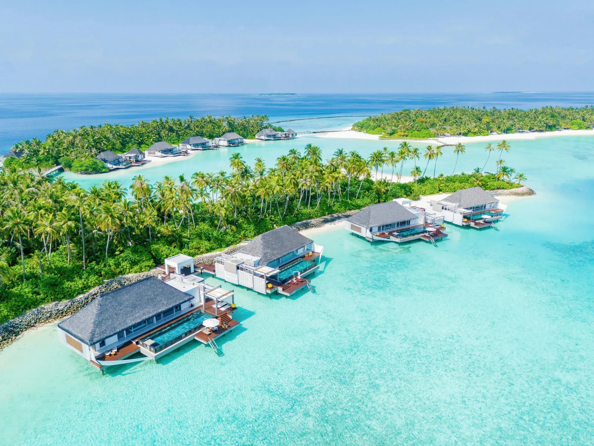 Aerial view of overwater villas on stilts above the turquoise lagoon at Cheval Blanc Randheli