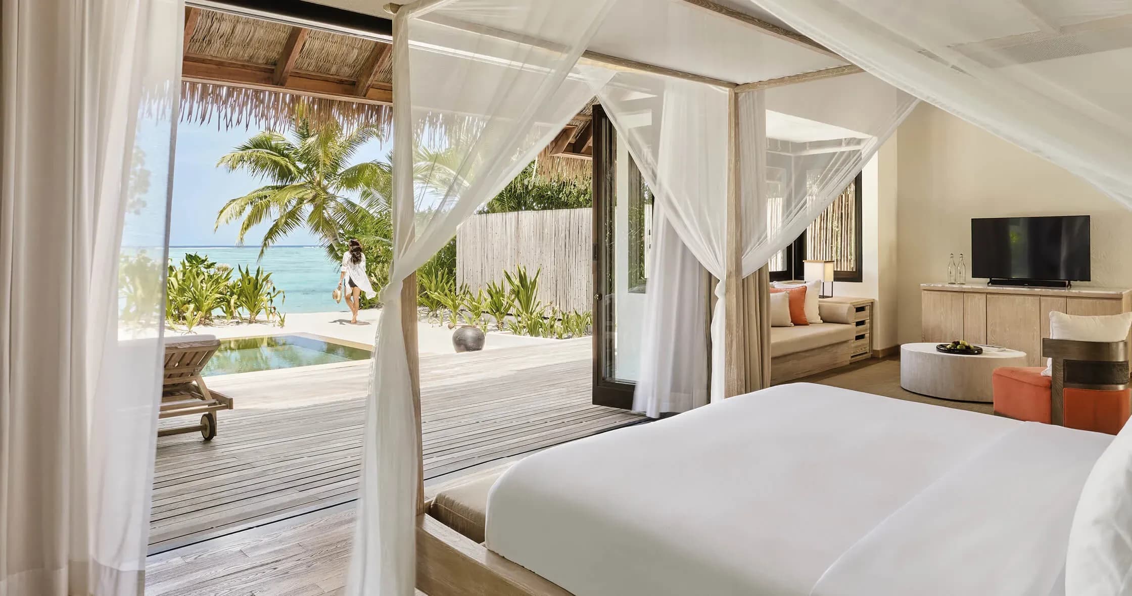 Beach Suite bedroom opening onto private pool and palm garden at COMO Maalifushi