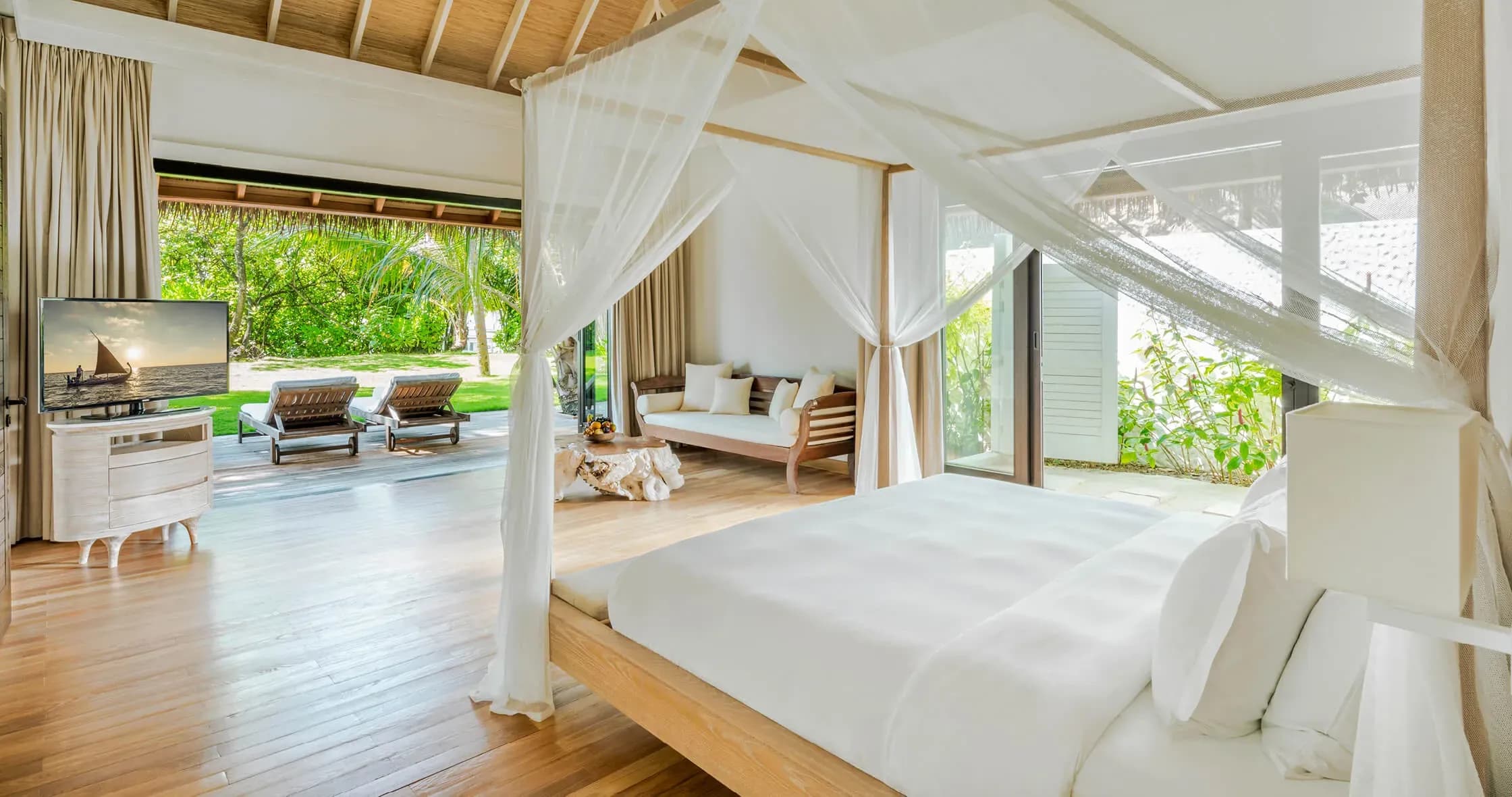 Maalifushi Beach Villa bedroom with canopy bed and garden views at COMO Maalifushi