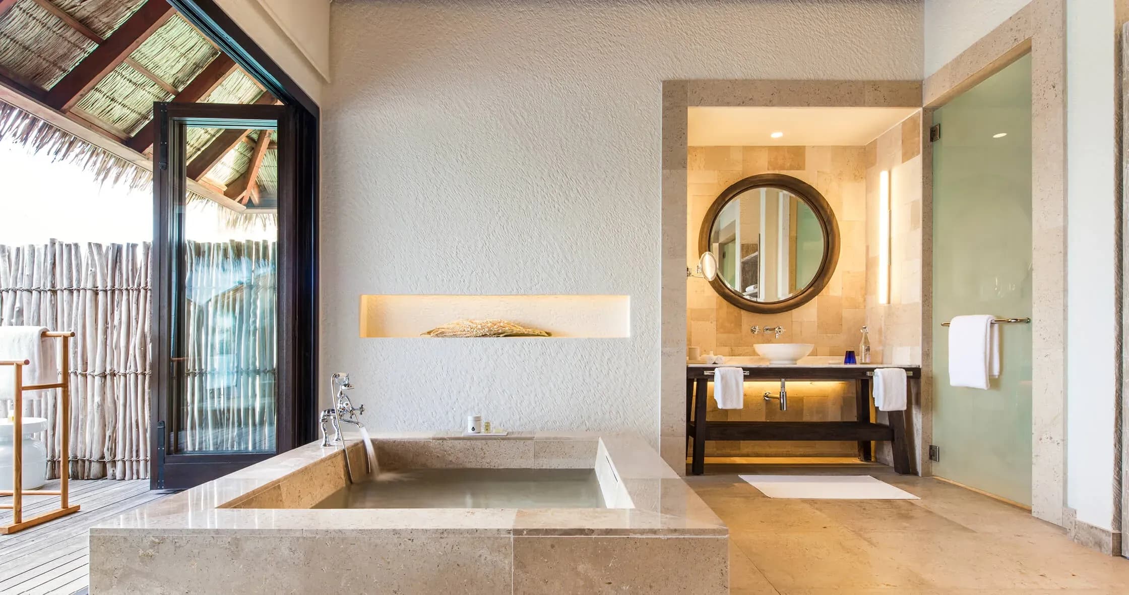 Water Villa bedroom opening onto private deck with ocean view at COMO Maalifushi