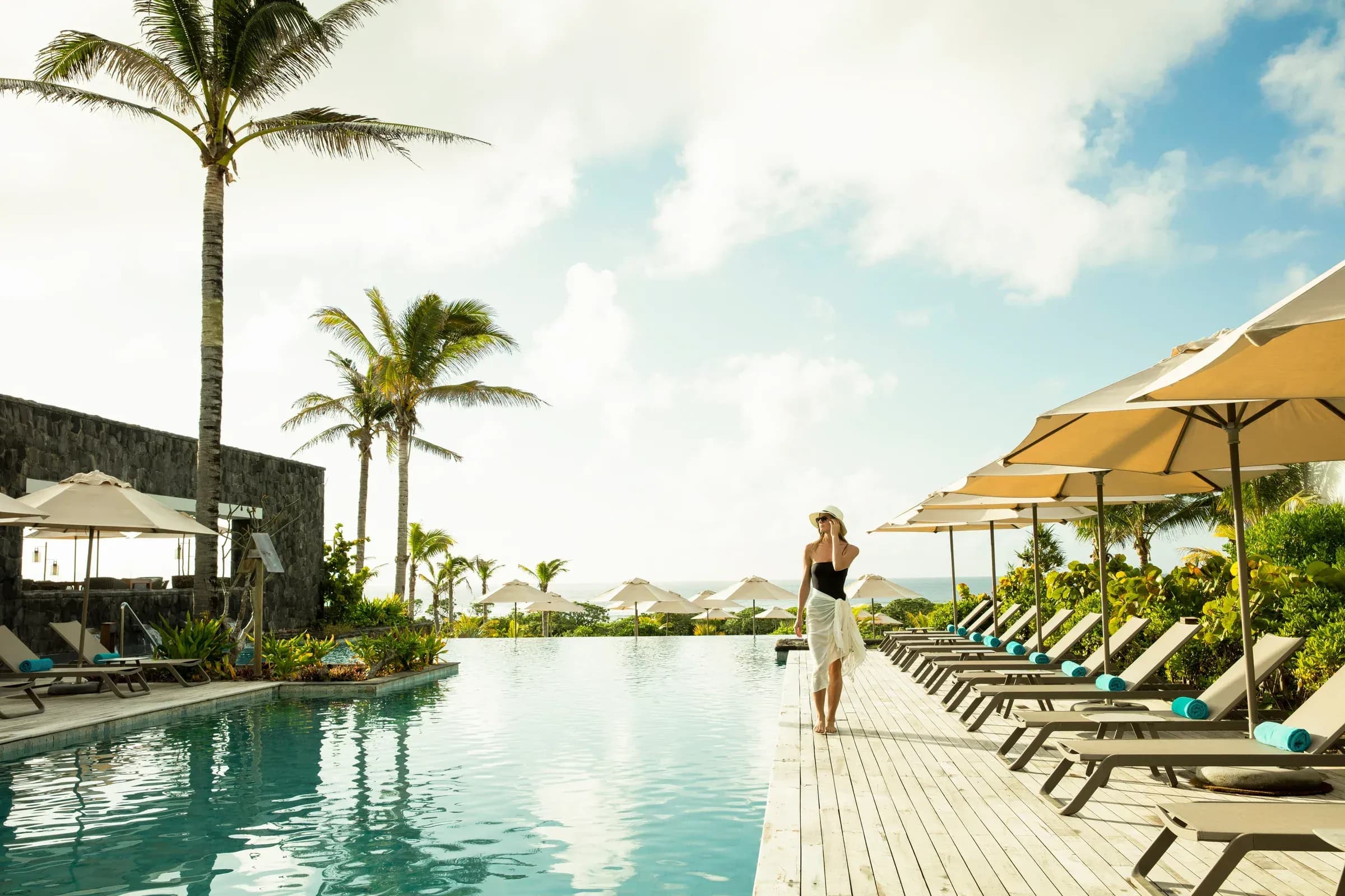 Infinity pool at Constance Le Chaland, with loungers and palm trees along the deck