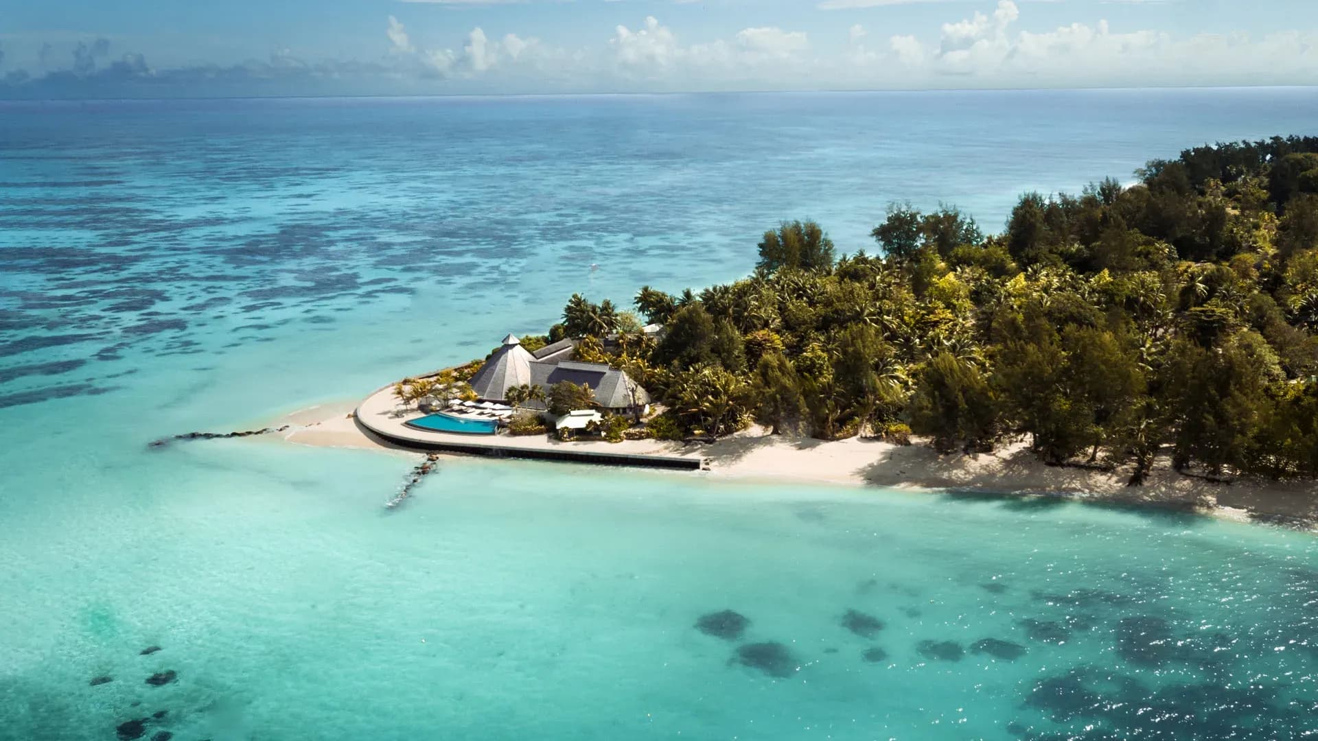 Aerial view of Denis Private Island's coral tip and thatched-roof lobby surrounded by turquoise lagoon, Seychelles