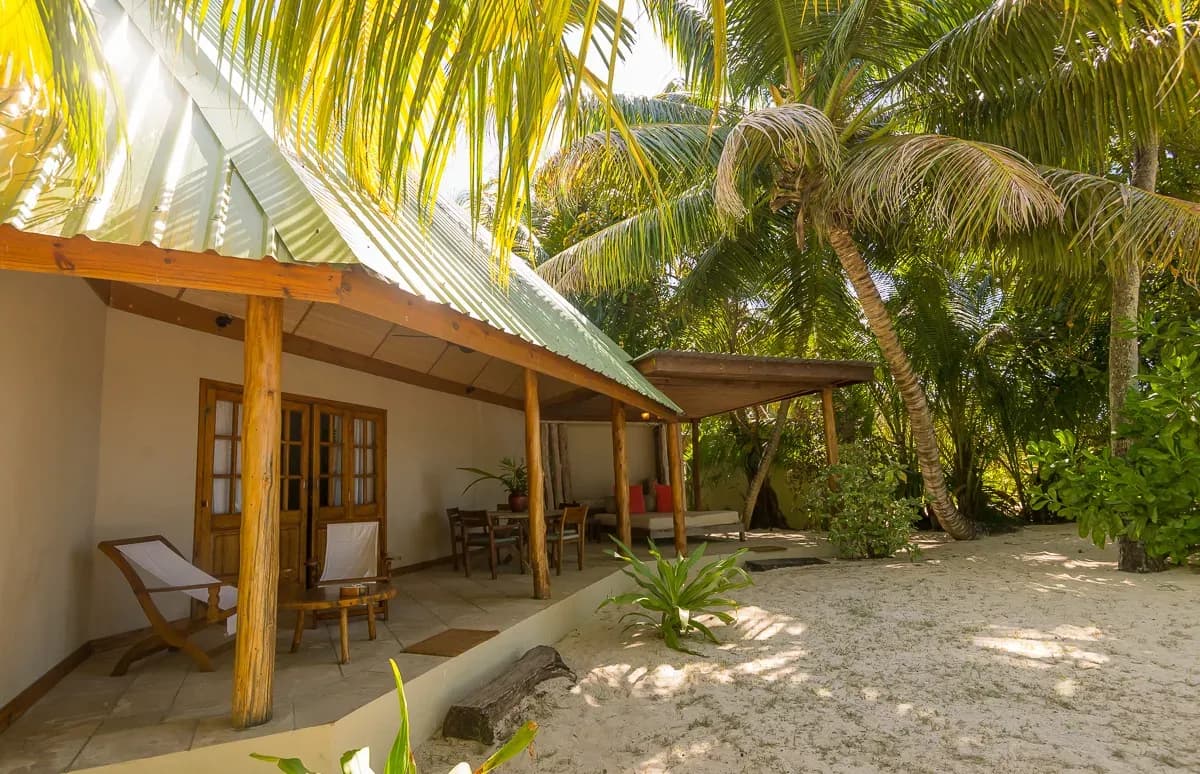 Beach Cottage verandah with wooden loungers on the sand at Denis Private Island