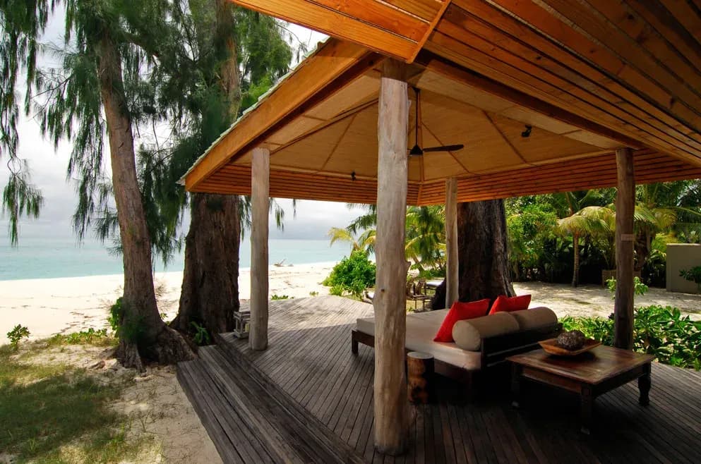 Beach Villa's wraparound verandah and day bed facing the beach at Denis Private Island