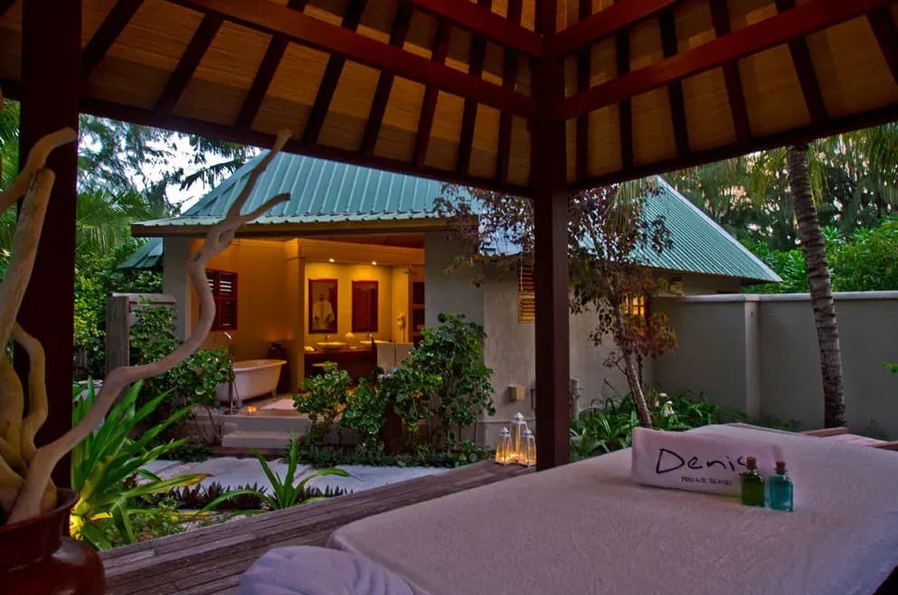 Beachfront Spa Cottage courtyard at dusk, with open-air bathroom and massage pavilion at Denis Private Island