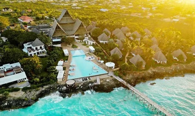 Aerial view of Essque Zalu Zanzibar's pool, jetty and Makuti-roofed pavilions above the coral shoreline