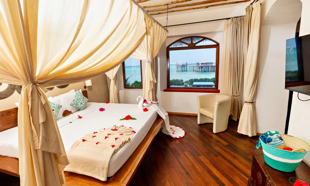 Ocean Suite bedroom with a view of the jetty through the window at Essque Zalu Zanzibar
