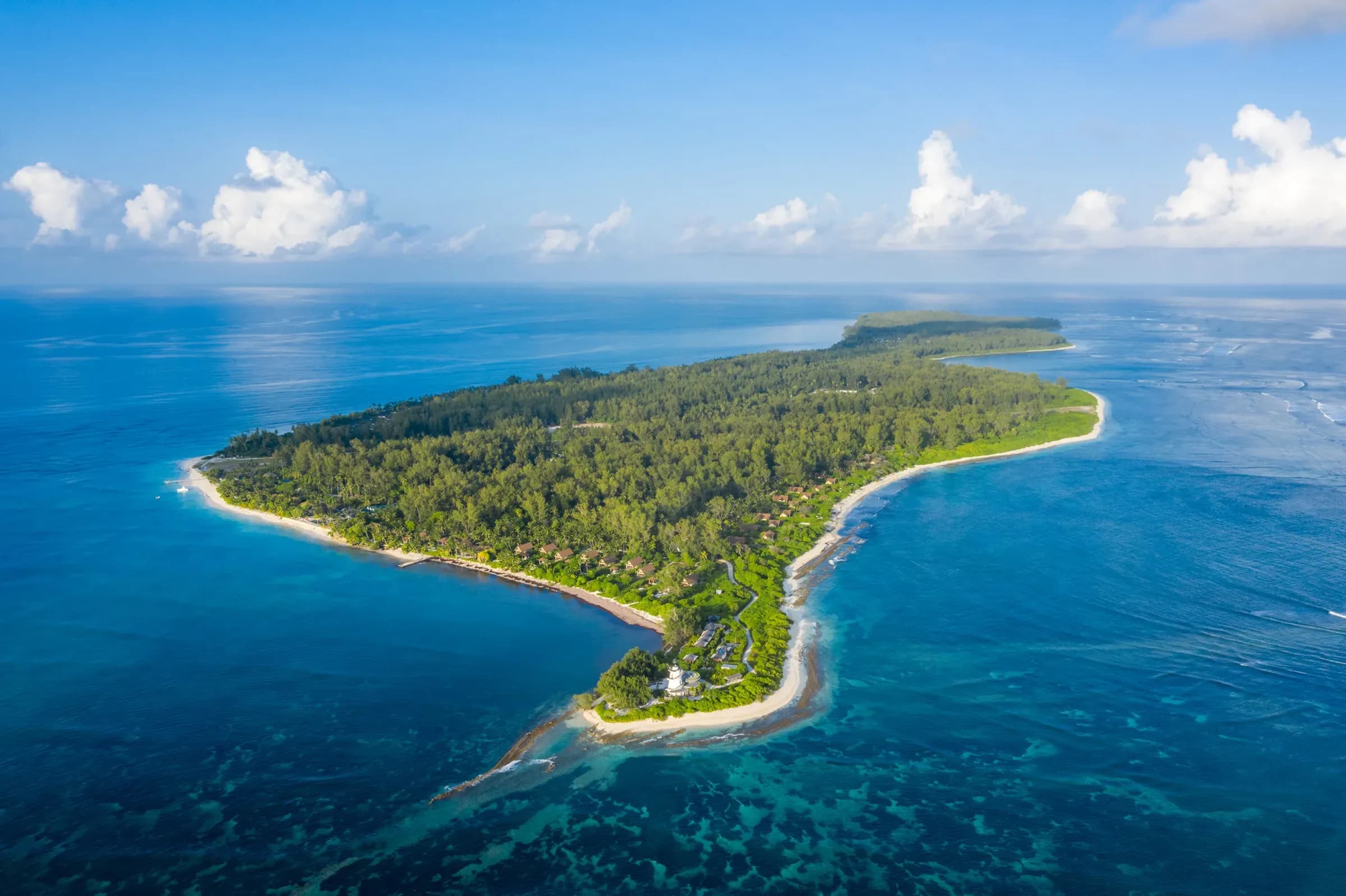 Aerial view of Four Seasons Resort Seychelles at Desroches Island, showing the coral atoll, lighthouse and lagoon
