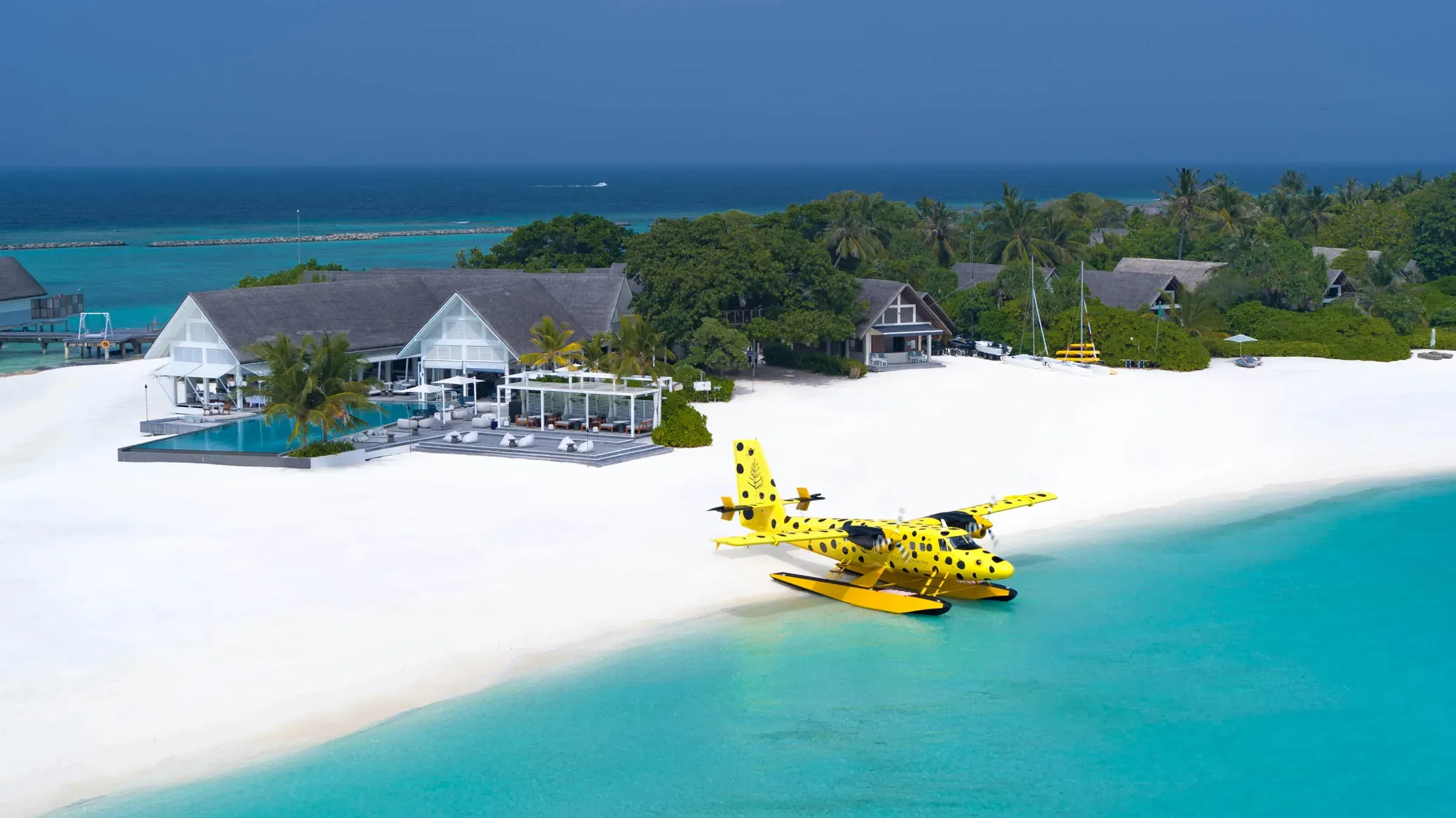 Aerial view of Four Seasons Resort Maldives at Landaa Giraavaru with a seaplane arriving on Blu Beach, Baa Atoll