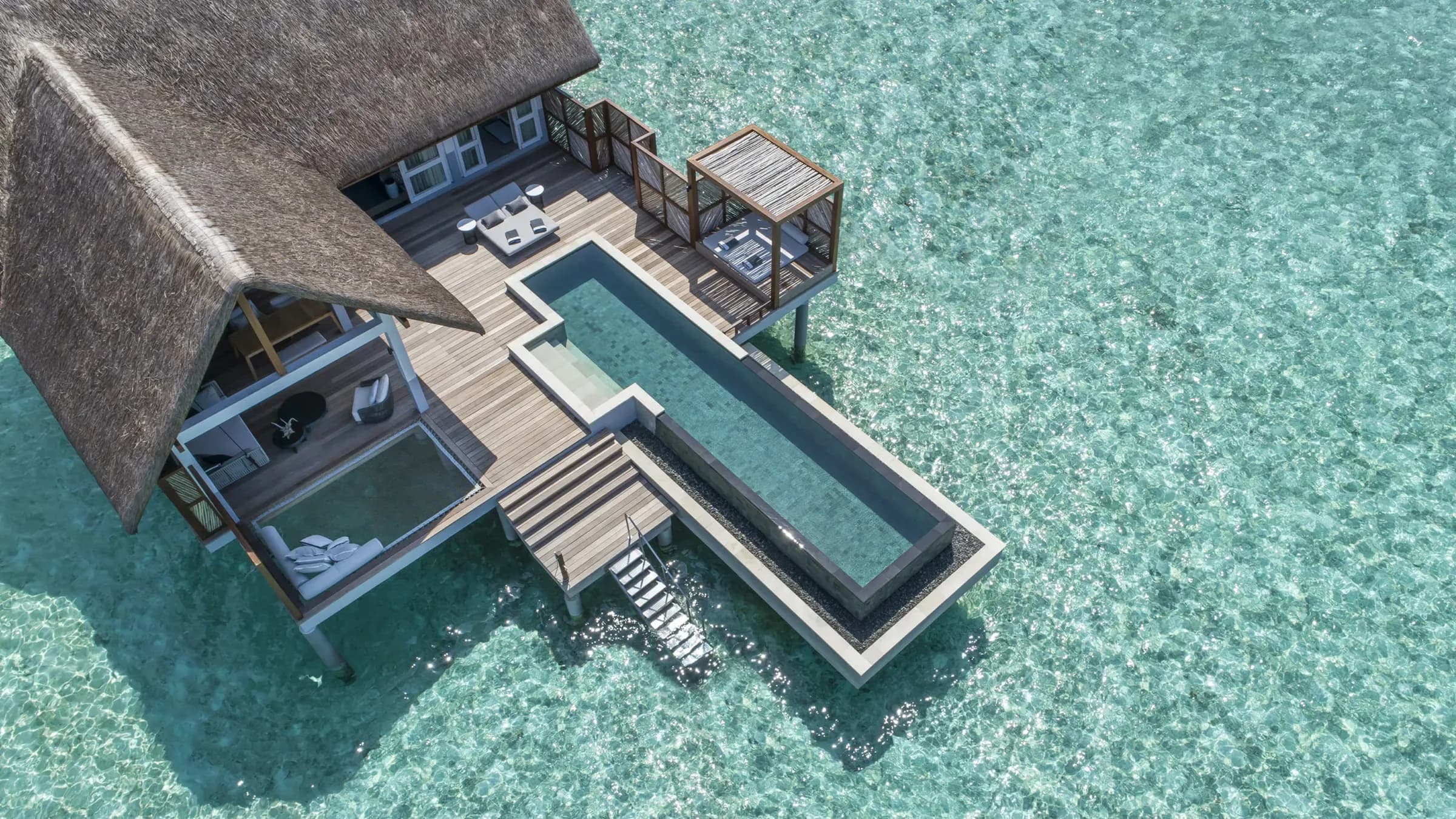 Aerial view of an overwater villa deck and plunge pool above the lagoon at Four Seasons Landaa Giraavaru