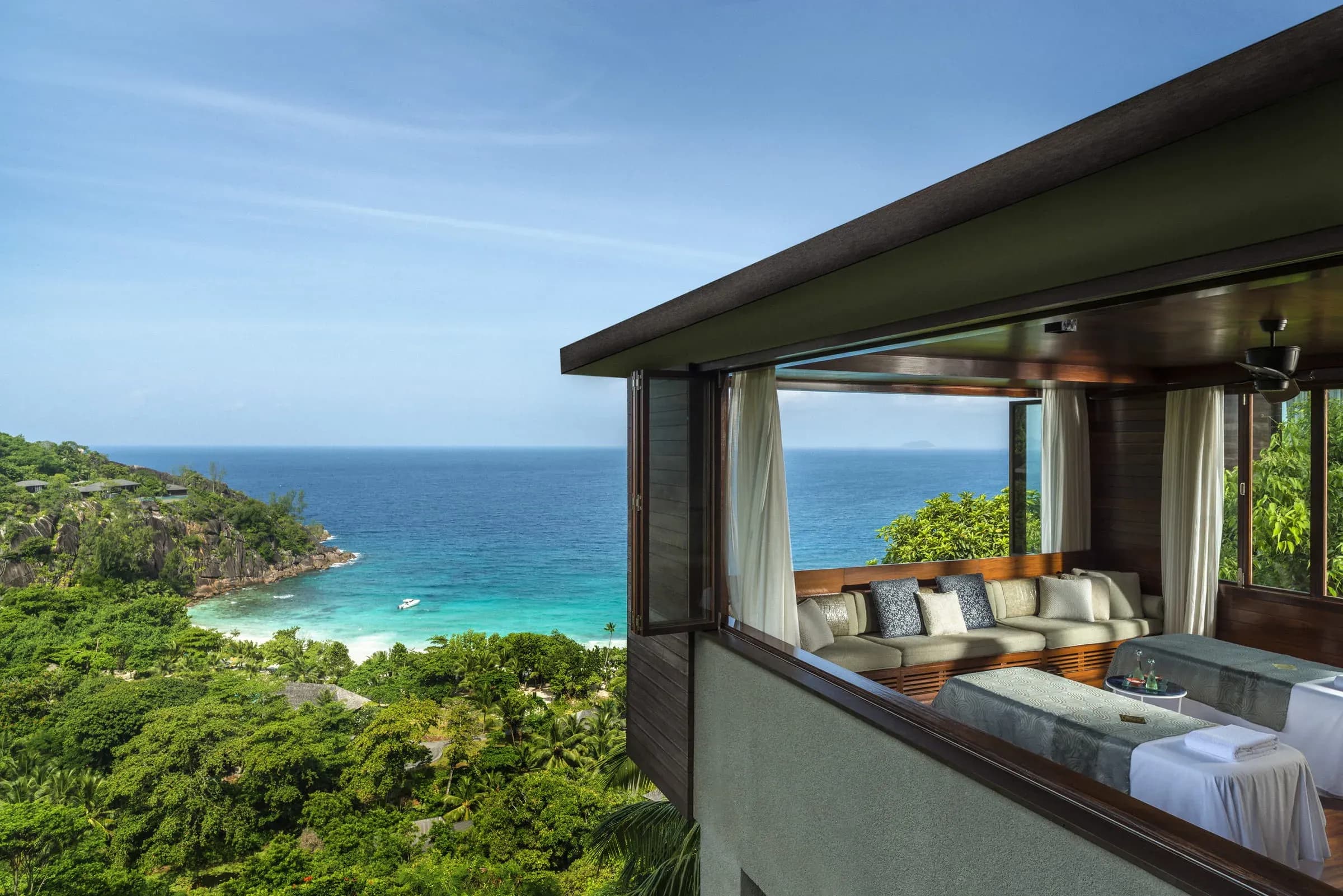 Two side-by-side massage tables in a spa treatment room high above the trees and ocean at Le Syel Spa