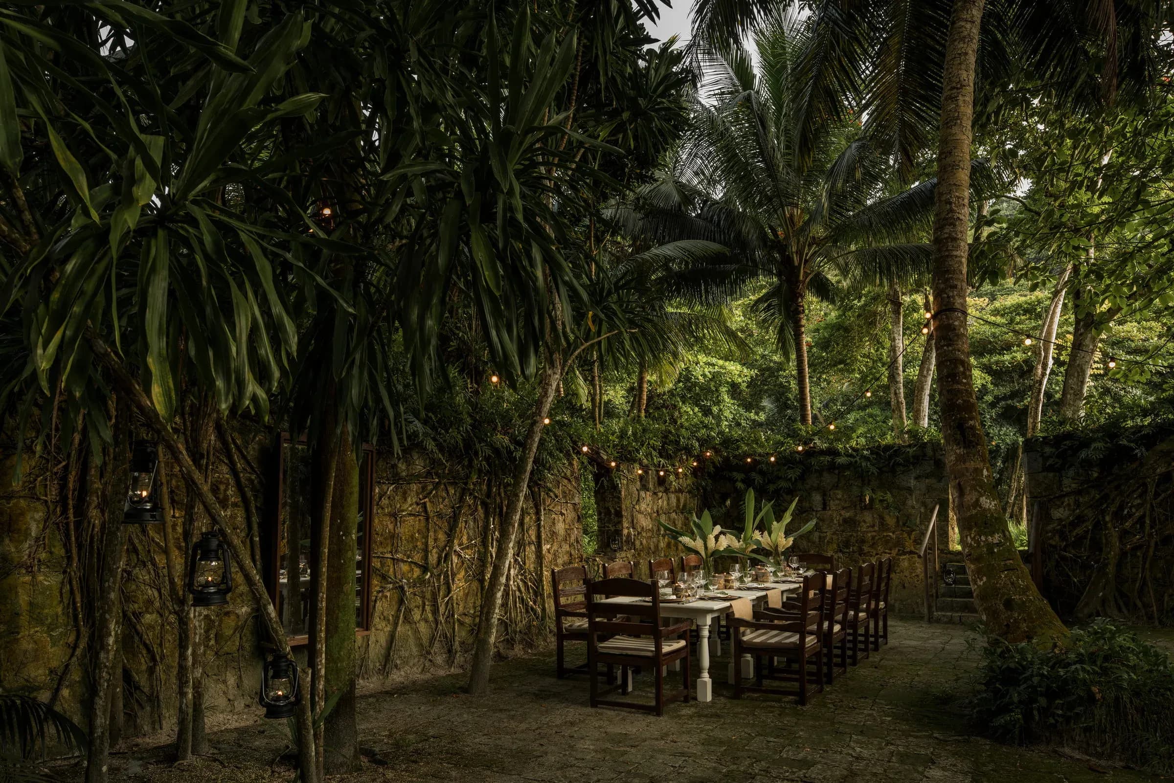 Long dining table set outdoors under palm leaves near the Foumba Creole ruins at Kannel restaurant