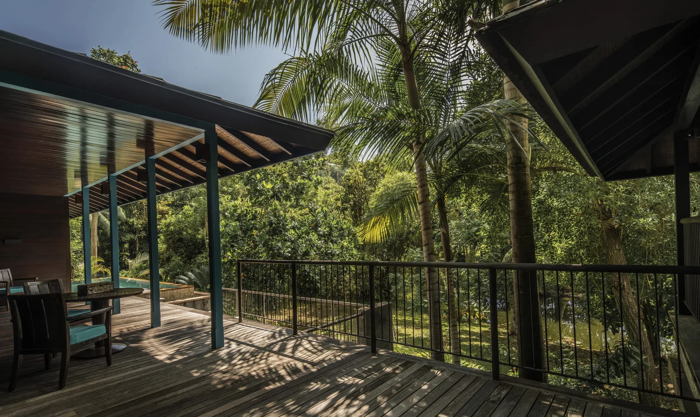 Palm trees cast shadows over the wood deck and roof of a Garden-View Villa at Four Seasons Resort Seychelles