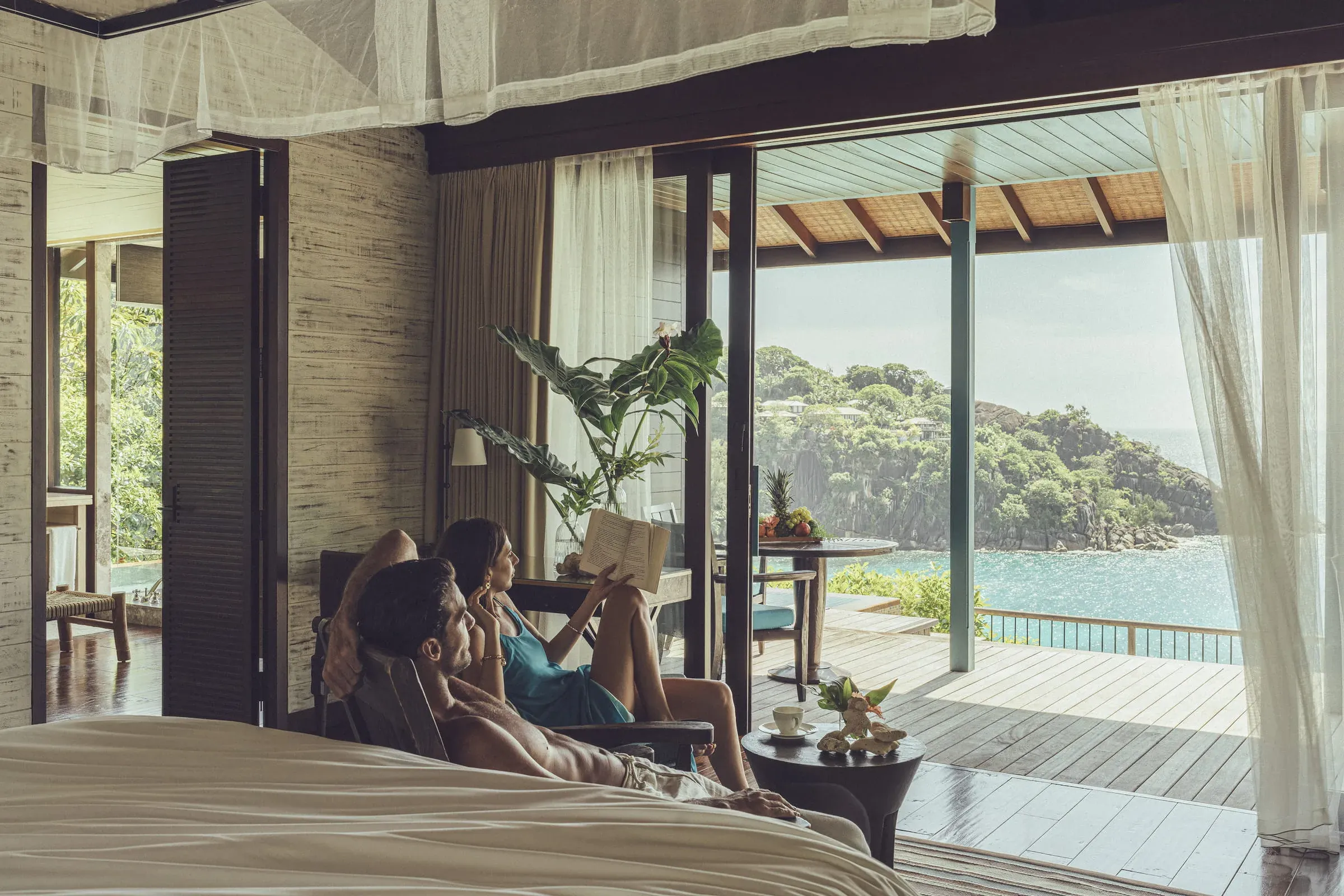 Villa bedroom opening to a covered deck with ocean views at the Hilltop Ocean-View Villa, Four Seasons Resort Seychelles