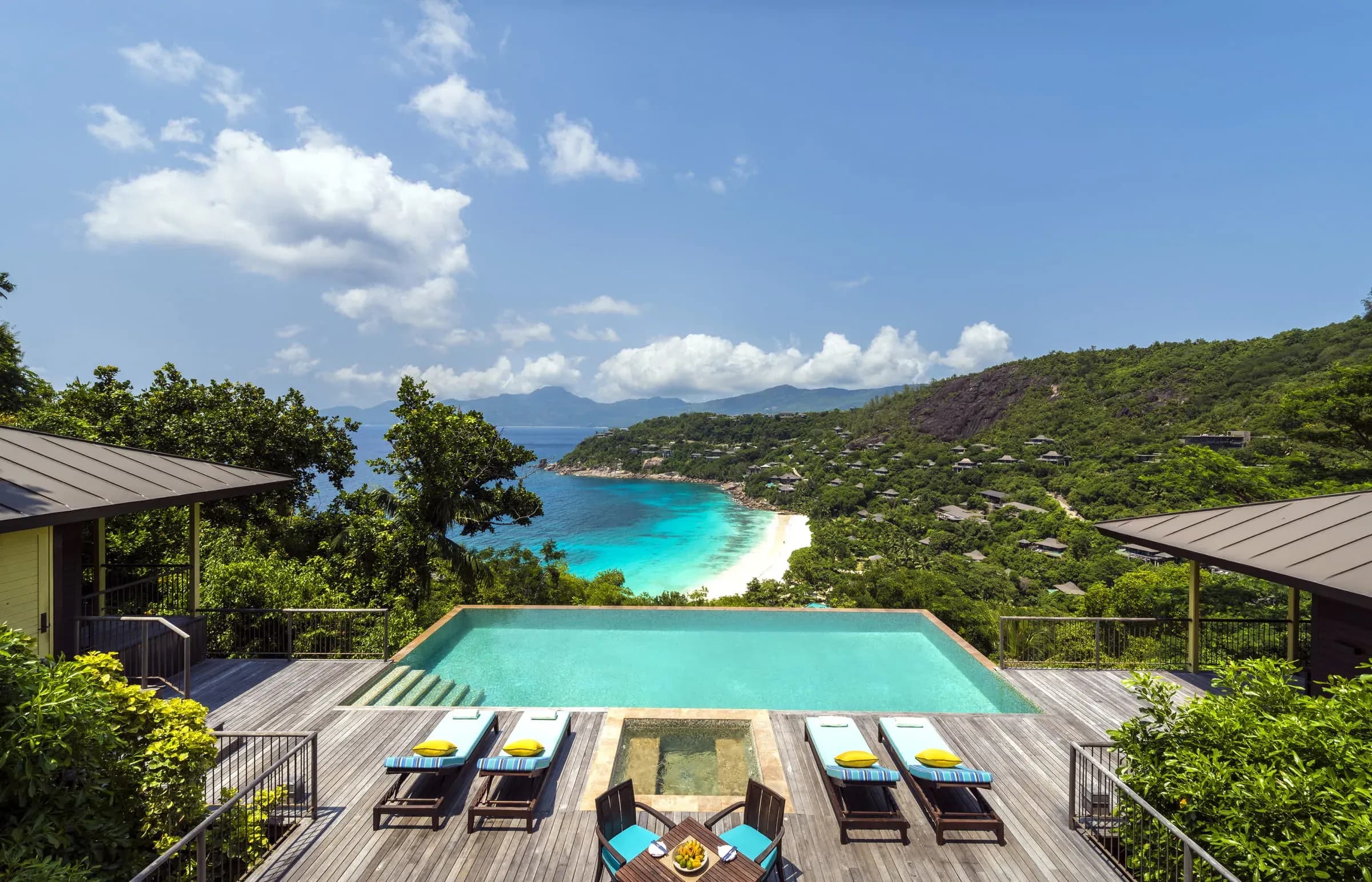 Patio with lounge chairs and hot tub overlooking the mountains and ocean at the Two-Bedroom Hilltop Ocean-View Suite