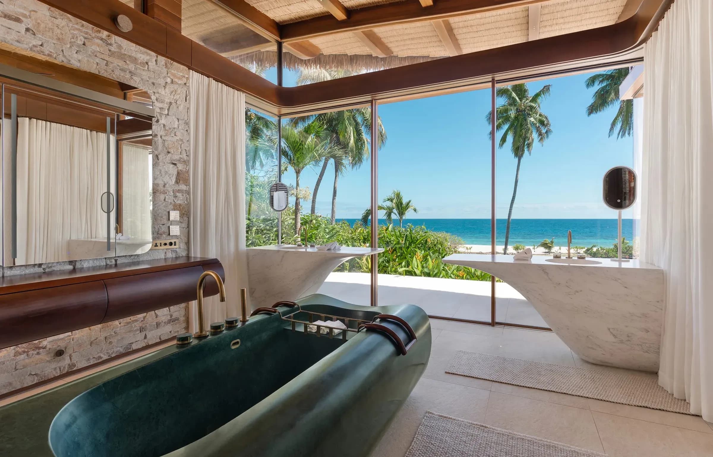 Freestanding stone bathtub facing the ocean in a Fregate villa bathroom
