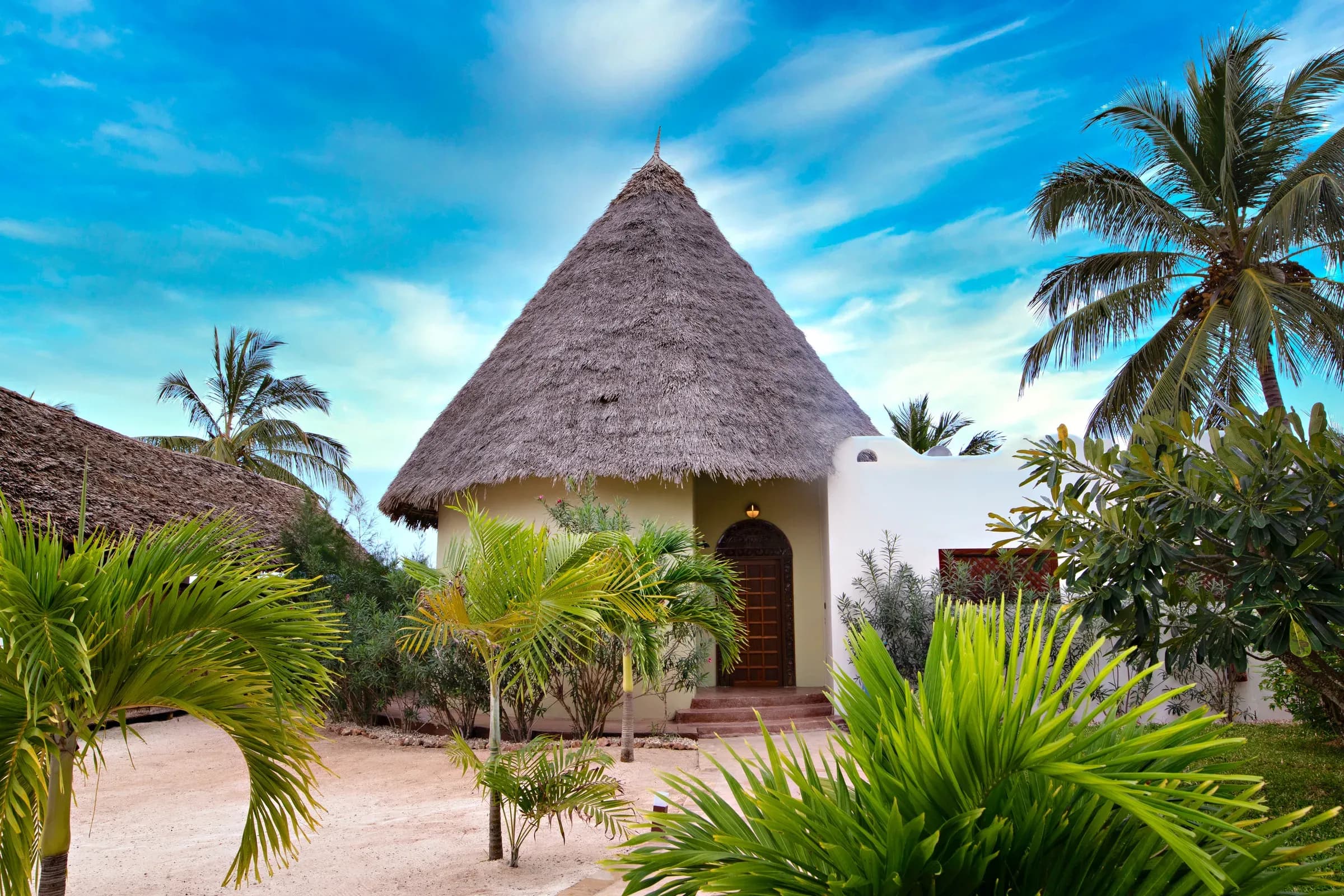 Luxury Beach Villa's thatched exterior among palm trees at Gold Zanzibar