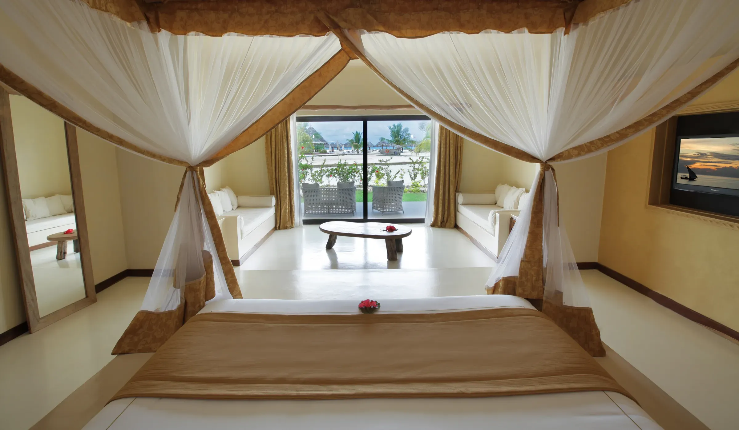 Suite bedroom with four-poster bed and lounge area at Gold Zanzibar
