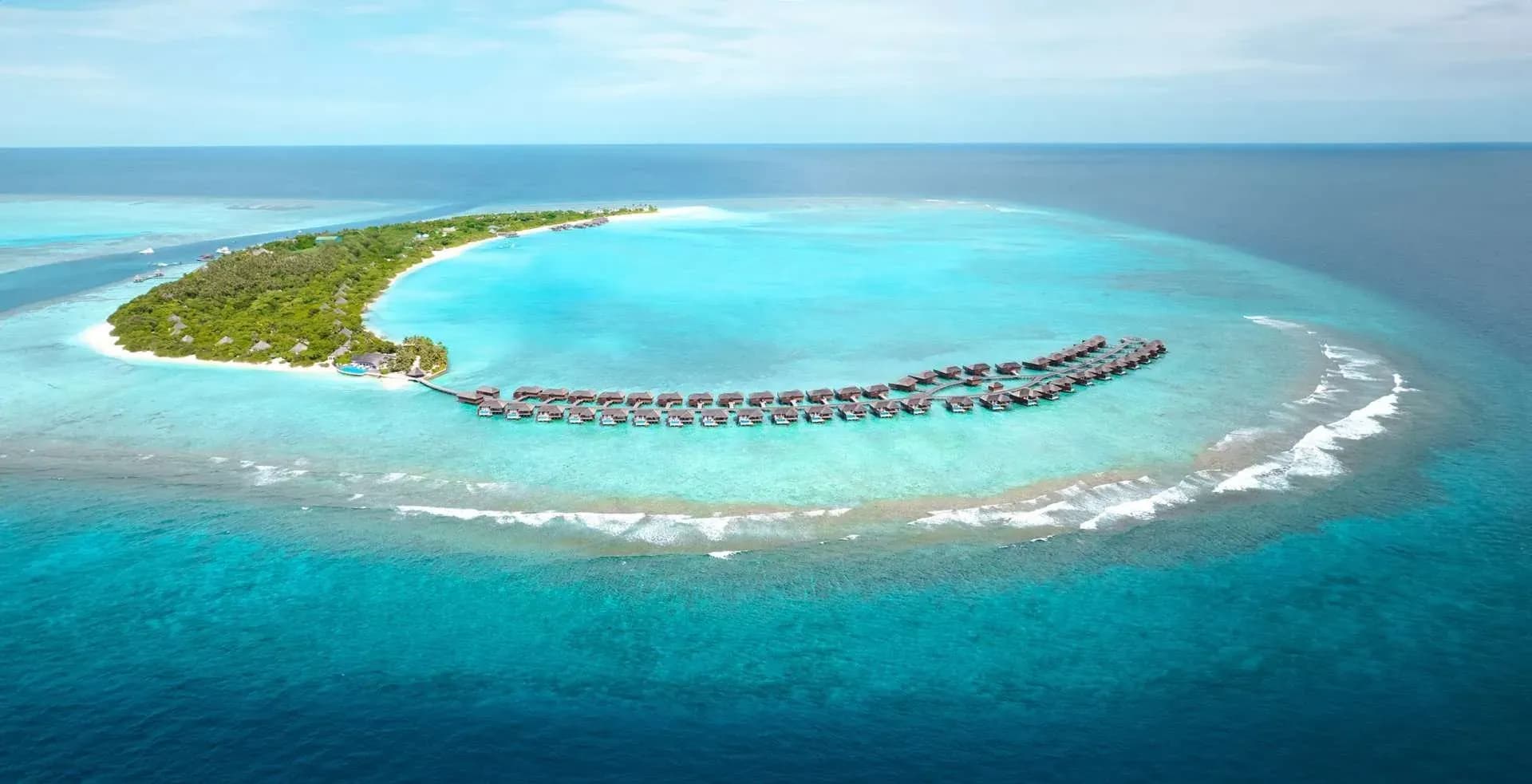 Aerial view of Hideaway Beach Resort & Spa's overwater villas curving out to the reef, Dhonakulhi Island, Maldives