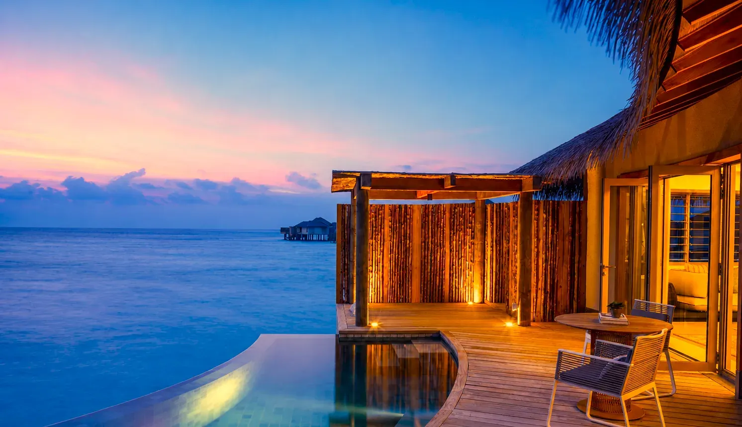 Sunset Overwater Pool Villa deck and infinity pool at InterContinental Maldives Maamunagau Resort