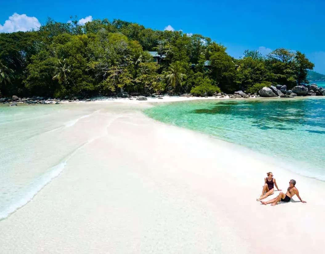 Couple relaxing on the white sandbar beach at JA Enchanted Island Resort, Seychelles