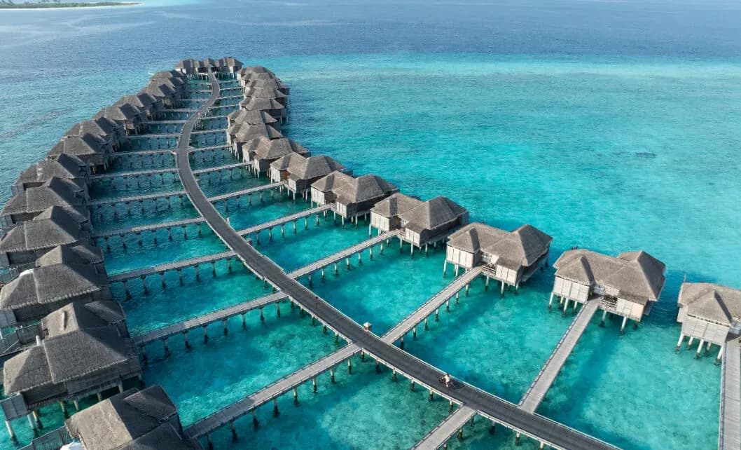 Aerial view of overwater villa jetties over turquoise lagoon at JA Manafaru