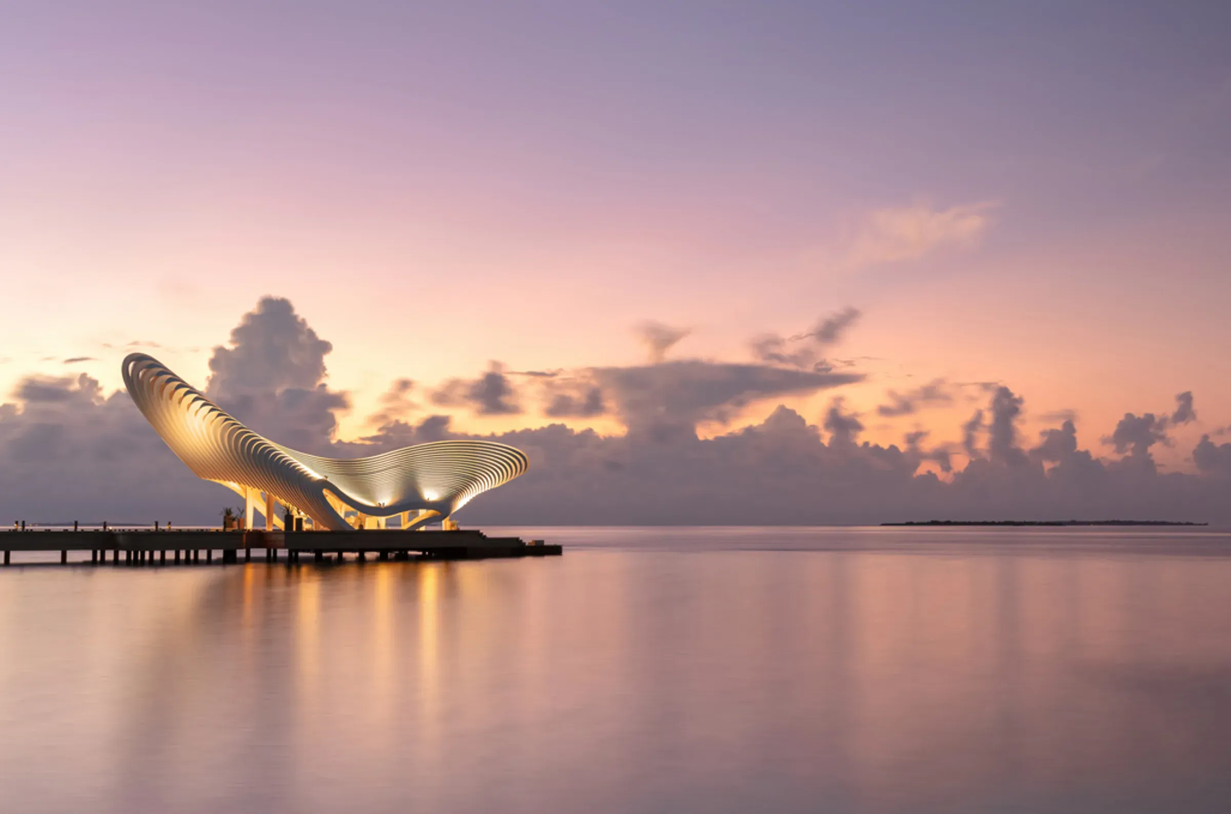The illuminated Gate of Zero pavilion at sunset over the lagoon at JOALI BEING, Raa Atoll