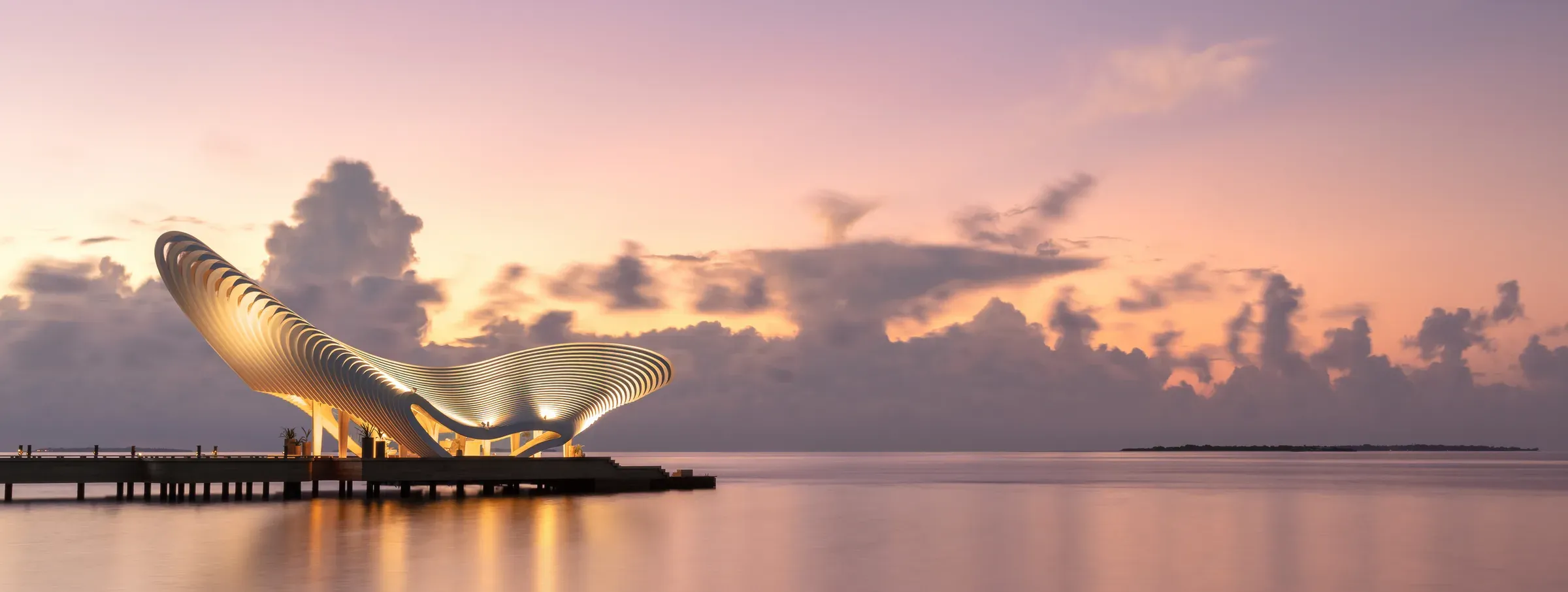 The sculptural Gate of Zero arrival pavilion lit at dusk on Bodufushi Island, JOALI BEING
