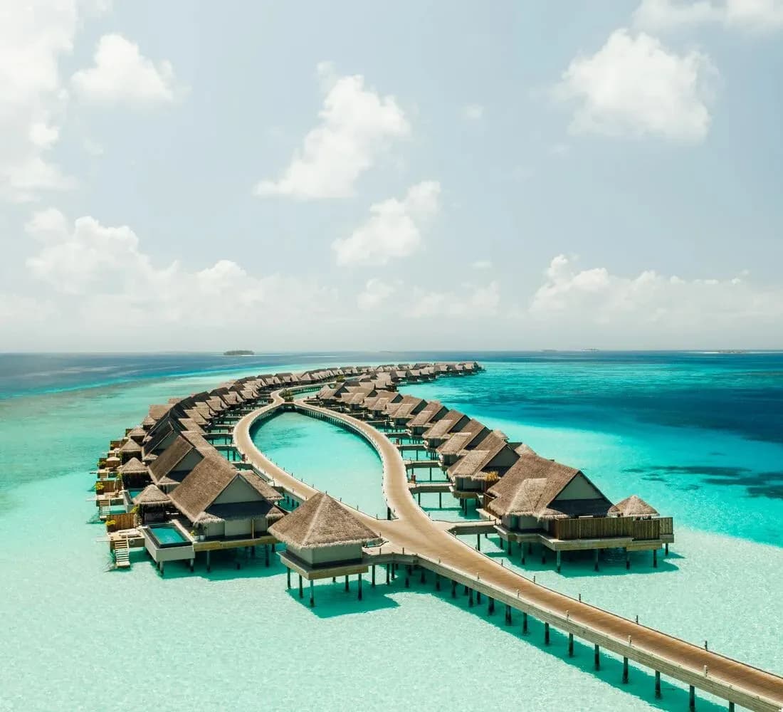 Aerial view of JOALI Maldives' overwater villas fringing the turquoise lagoon