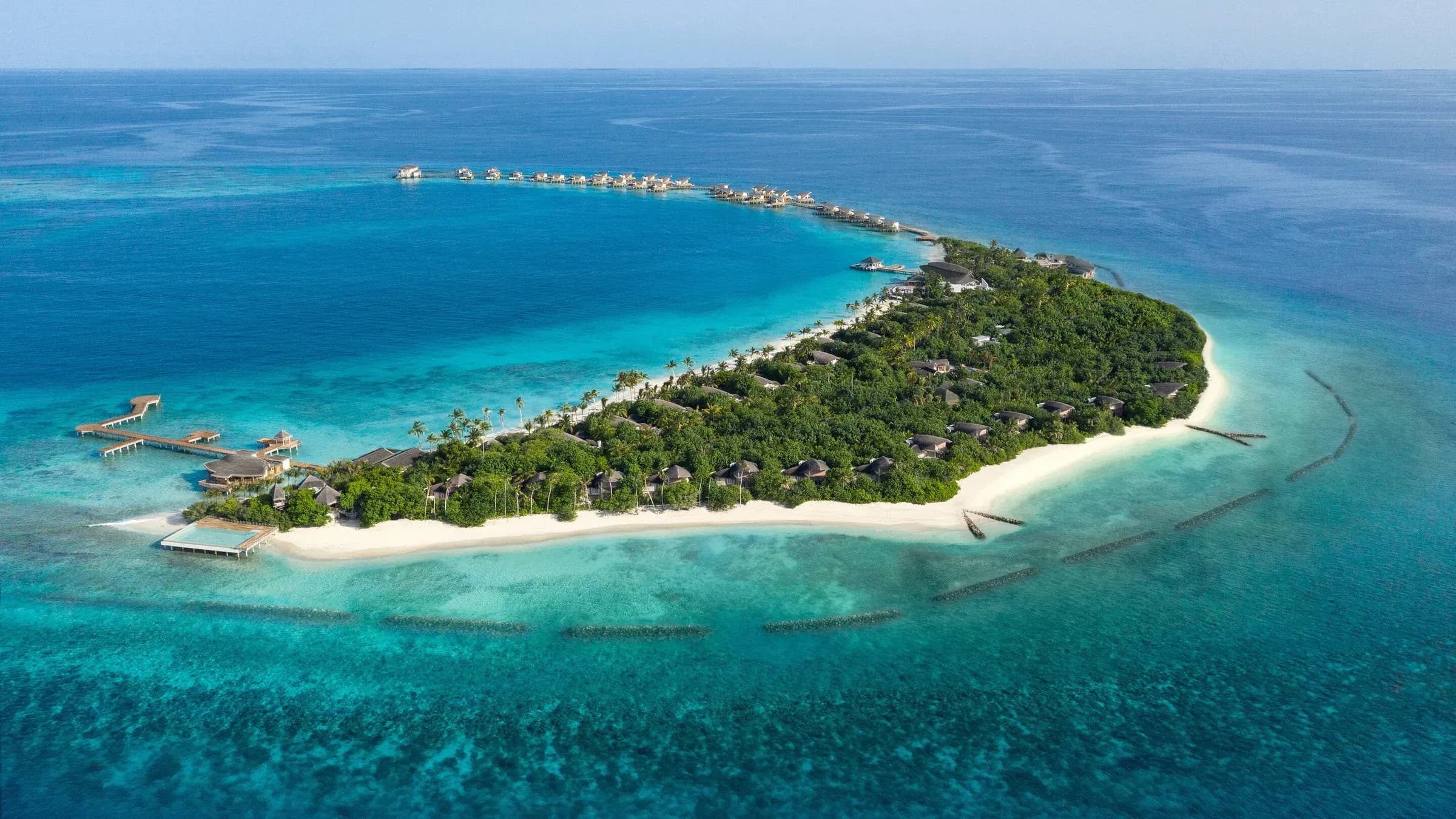 Aerial view of JW Marriott Maldives Resort & Spa on Vagaru Island, Shaviyani Atoll, showing overwater villas and the surrounding reef