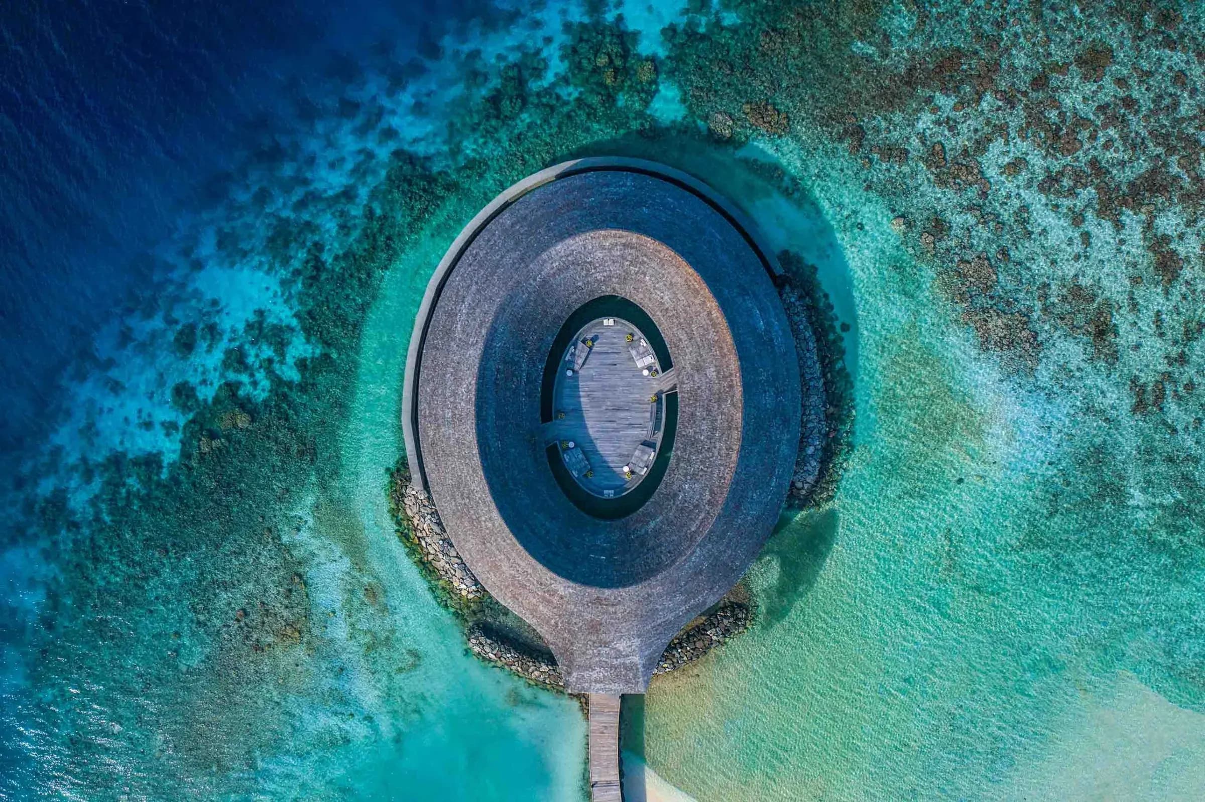 Aerial view of the ring-shaped overwater Baani Spa pavilion at Kagi Maldives