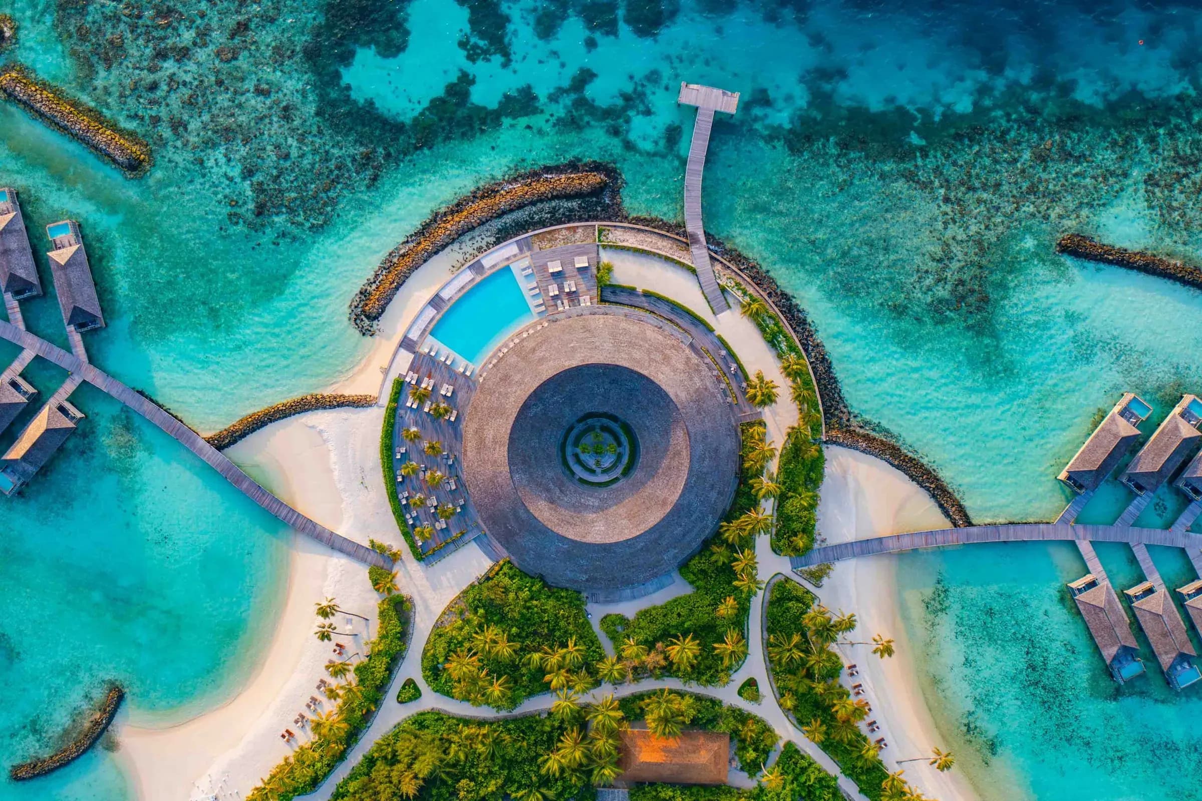 Aerial view of Kagi Maldives Resort & Spa's circular beach pavilion and turquoise lagoon, North Malé Atoll