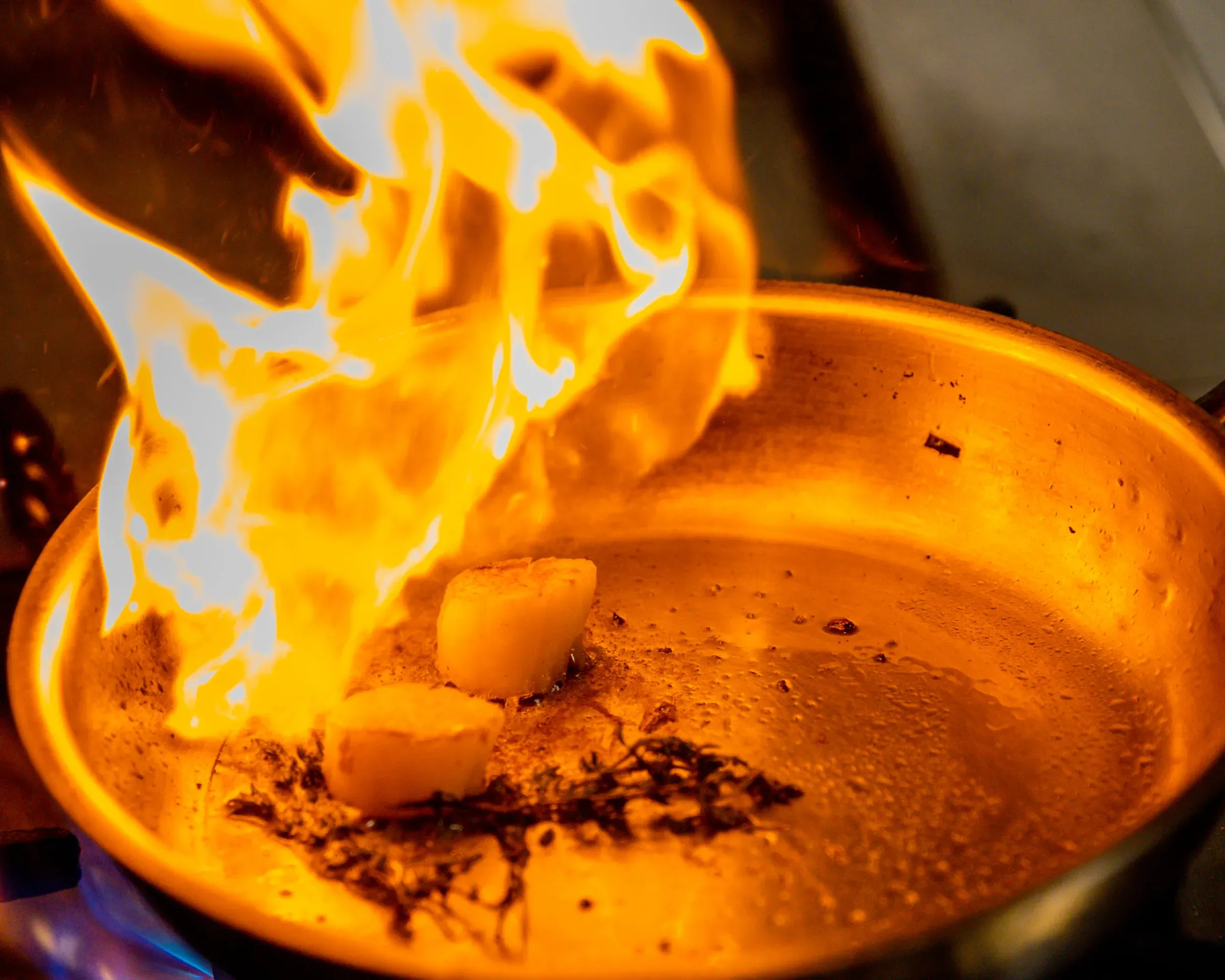 Chef flambeing scallops in the show kitchen at Ke-Un restaurant, Kagi Maldives