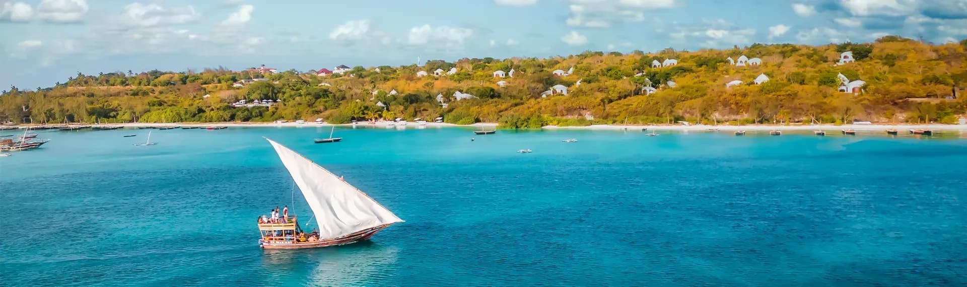 Traditional dhow under sail off Kendwa with Kilindi Zanzibar's pavilions visible on the headland