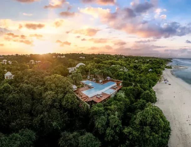 Aerial view at dusk of Kilindi Zanzibar's infinity pool set above the beach and Indian Ocean