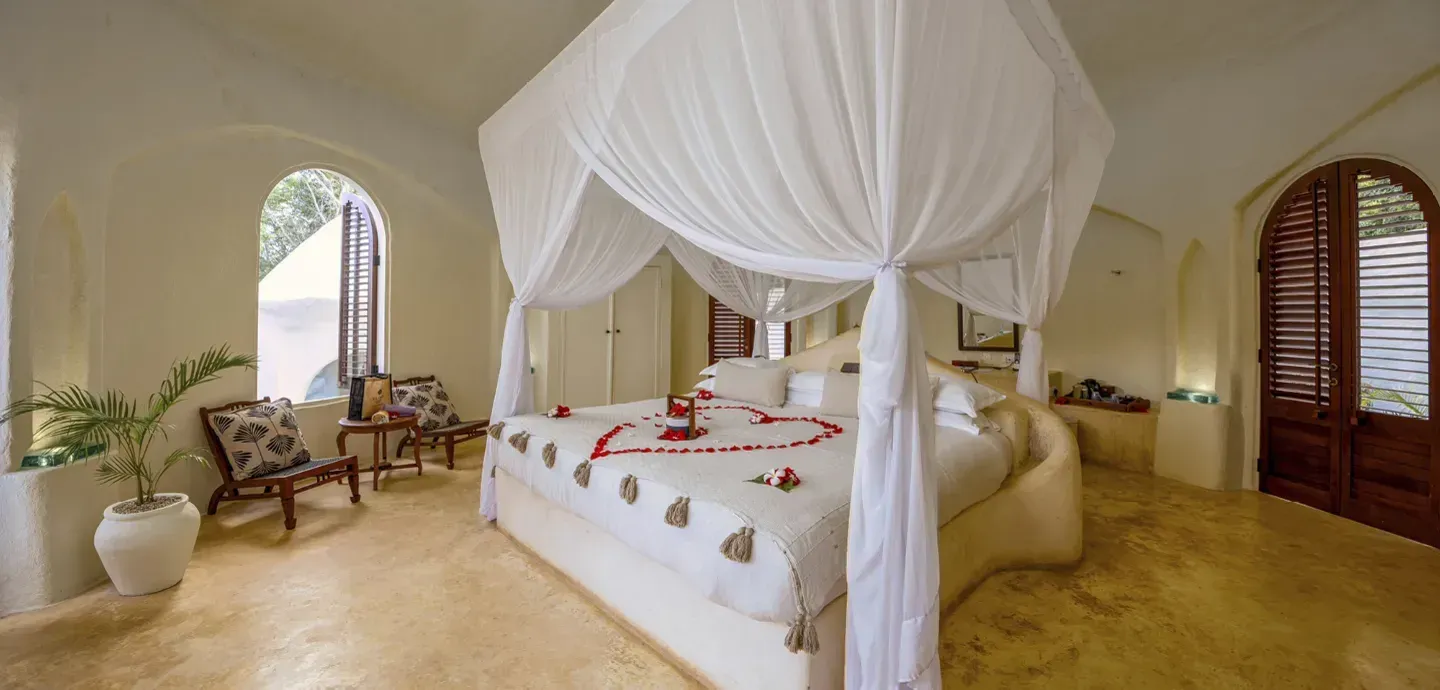 Luxury Garden View Villa bedroom at Kilindi Zanzibar with four-poster bed and wooden shuttered windows