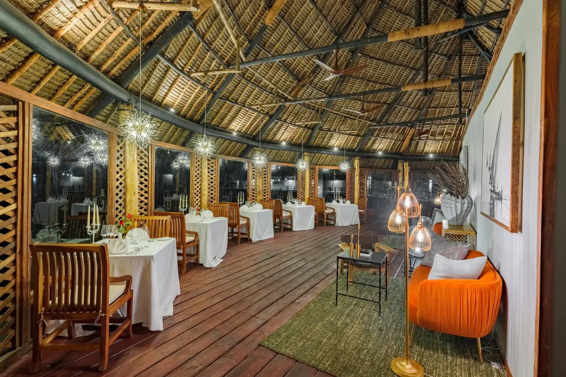 Candlelit dining tables inside the overwater Isaraya Restaurant & Bar pavilion at night
