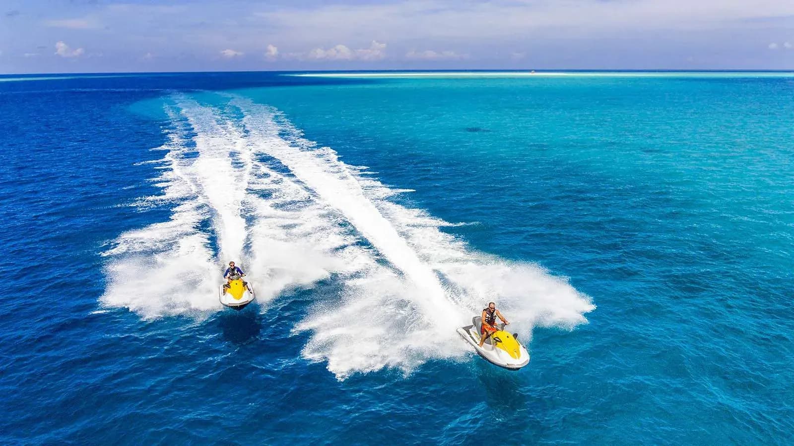 Guests riding jet skis across the lagoon at Kudadoo Maldives Private Island