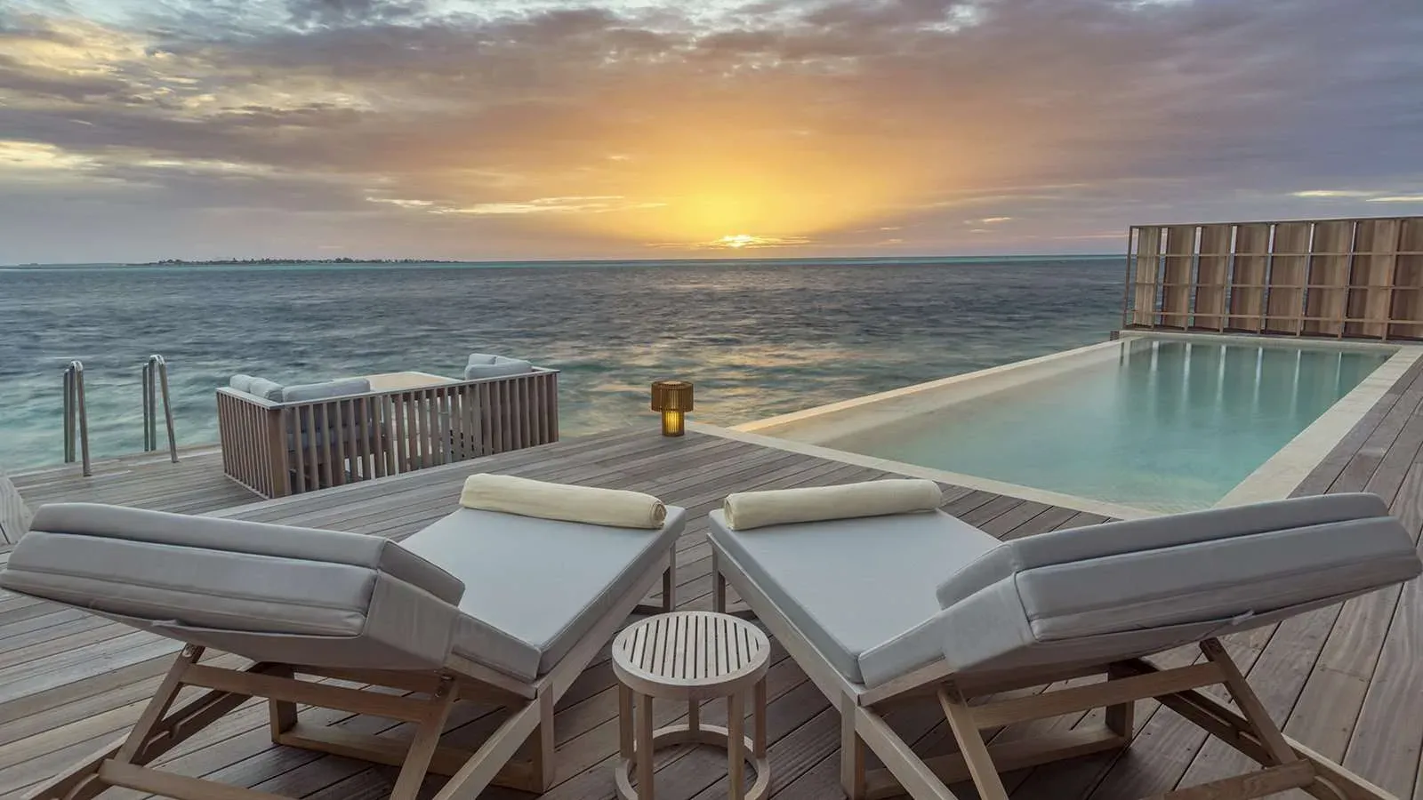 Sunset over the ocean from a residence deck and infinity pool at Kudadoo Maldives Private Island